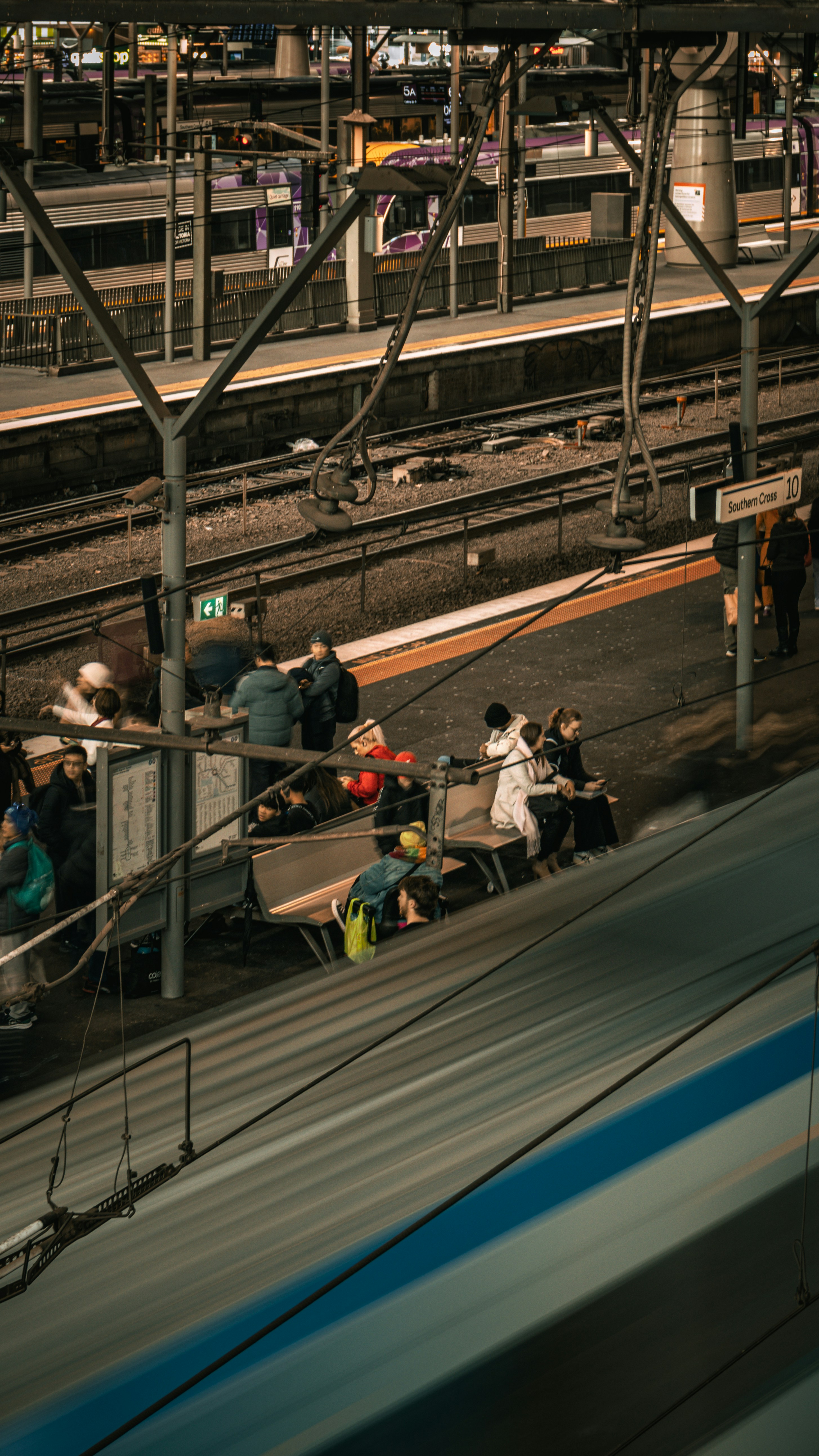 Los viajeros esperan en un andén de tren con trenes que pasan.