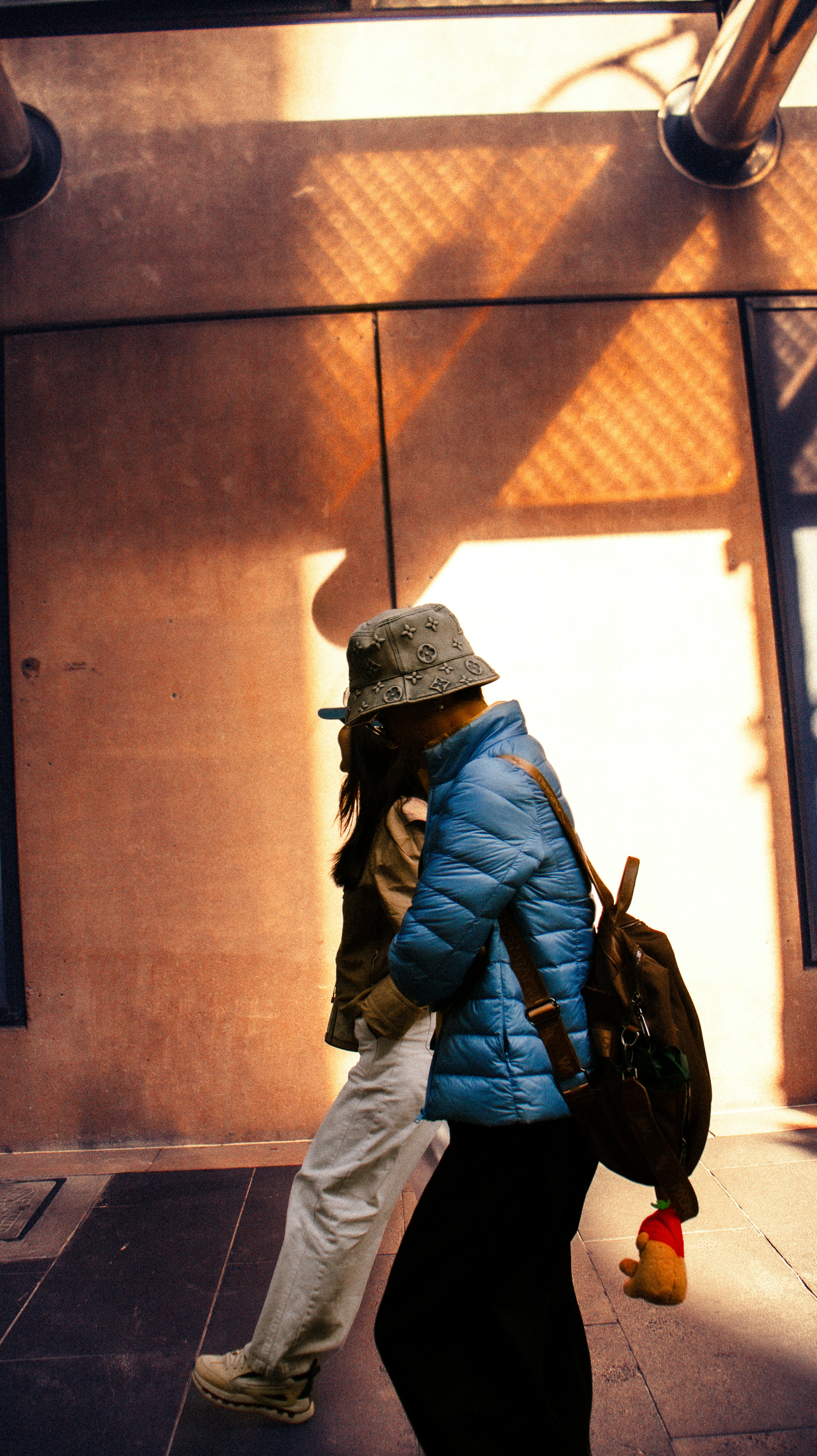 Two people walking with a backpack and a stuffed toy.