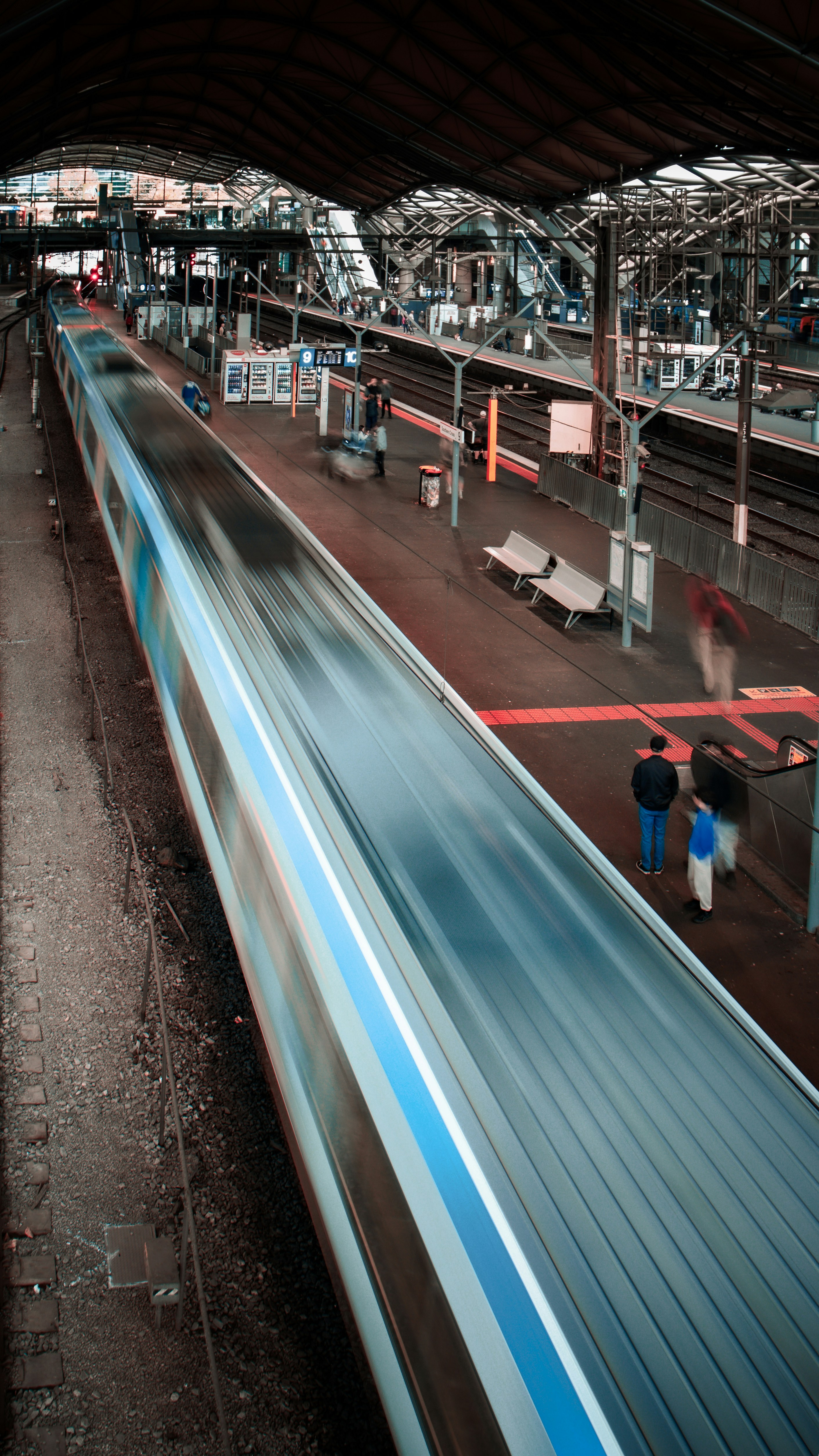 Un tren pasando a toda velocidad por una estación con movimiento borroso.