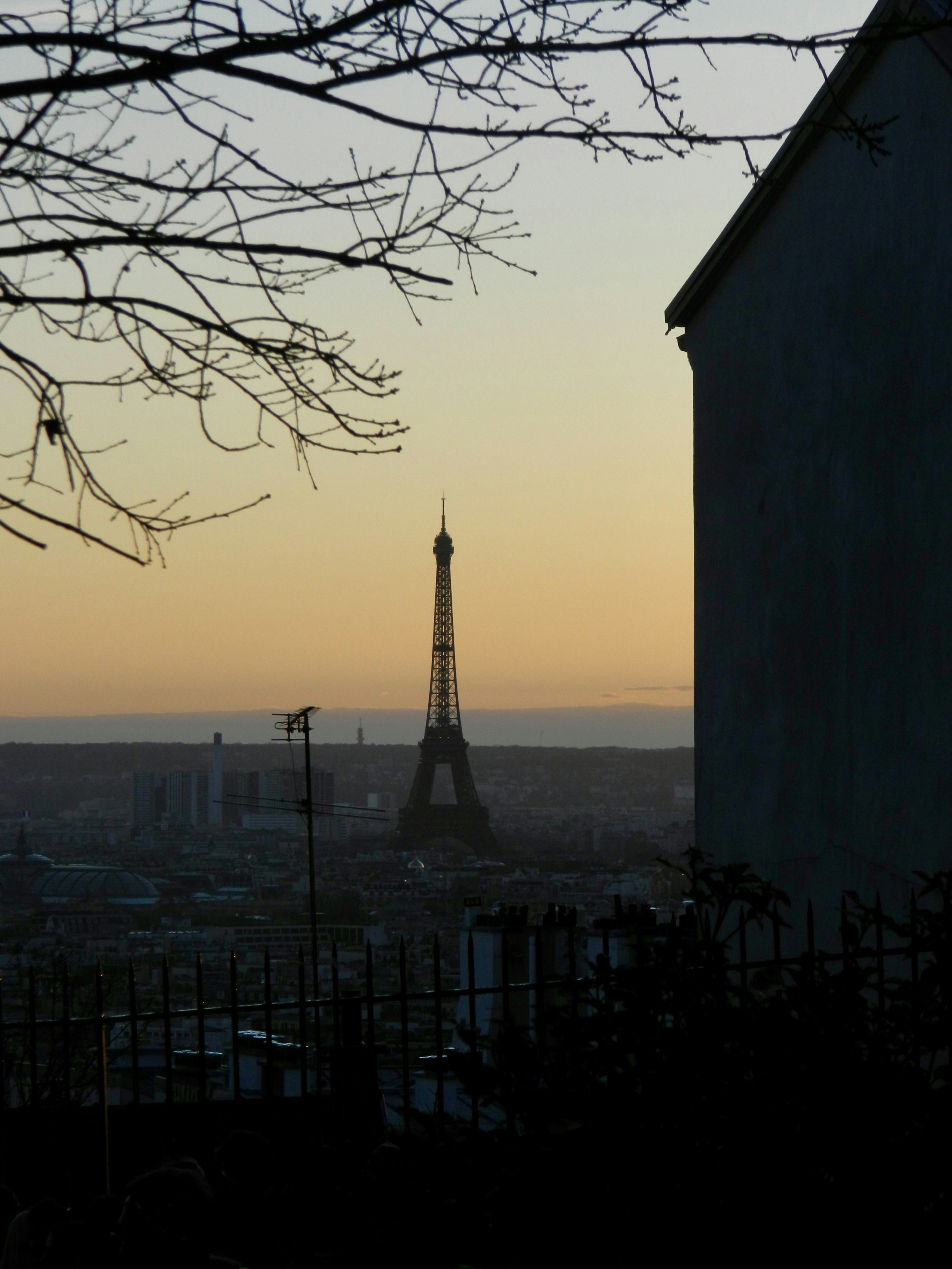 La Torre Eiffel stagliata contro un cielo nebbioso al tramonto.