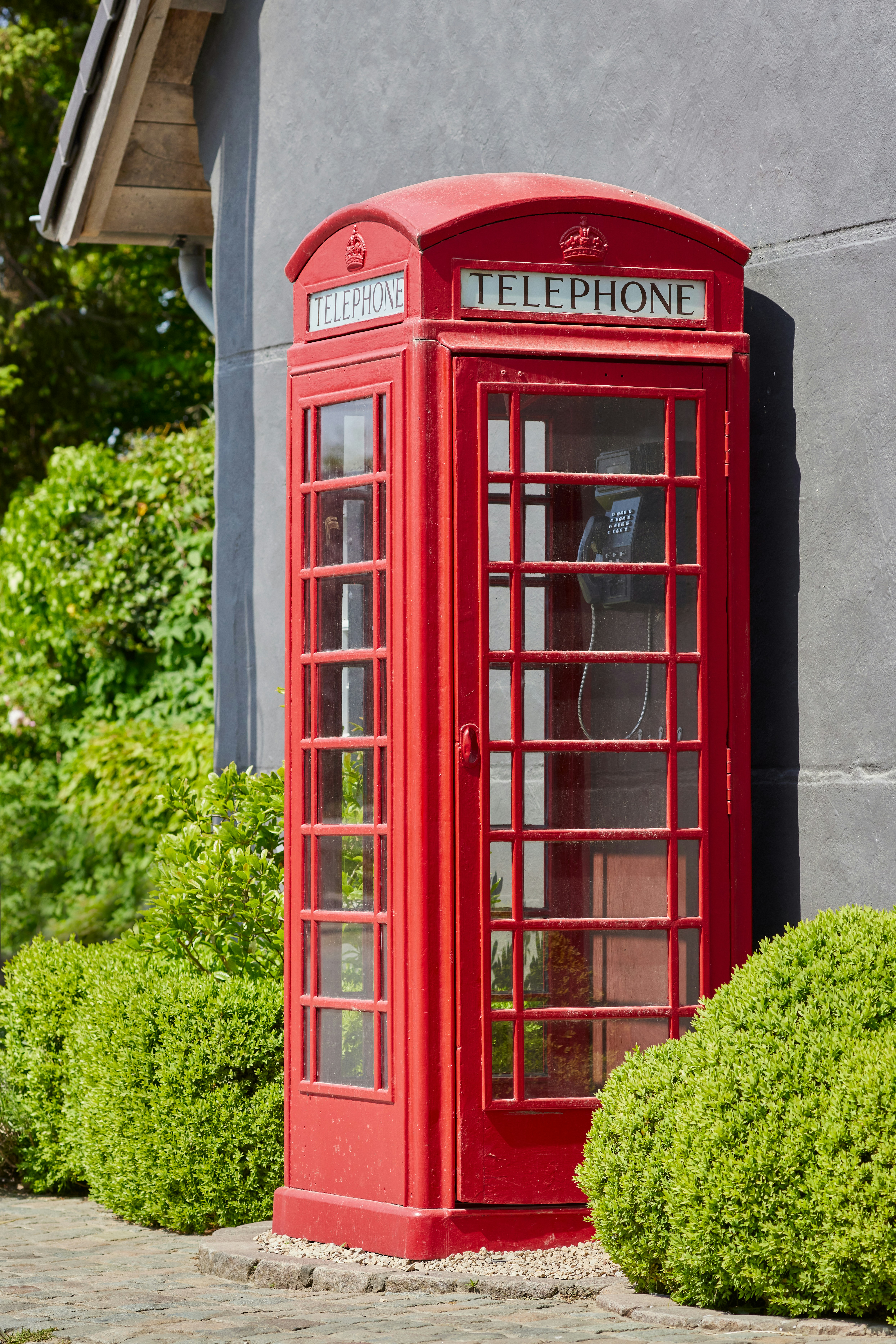 Une cabine téléphonique britannique rouge classique se trouve à l’extérieur.