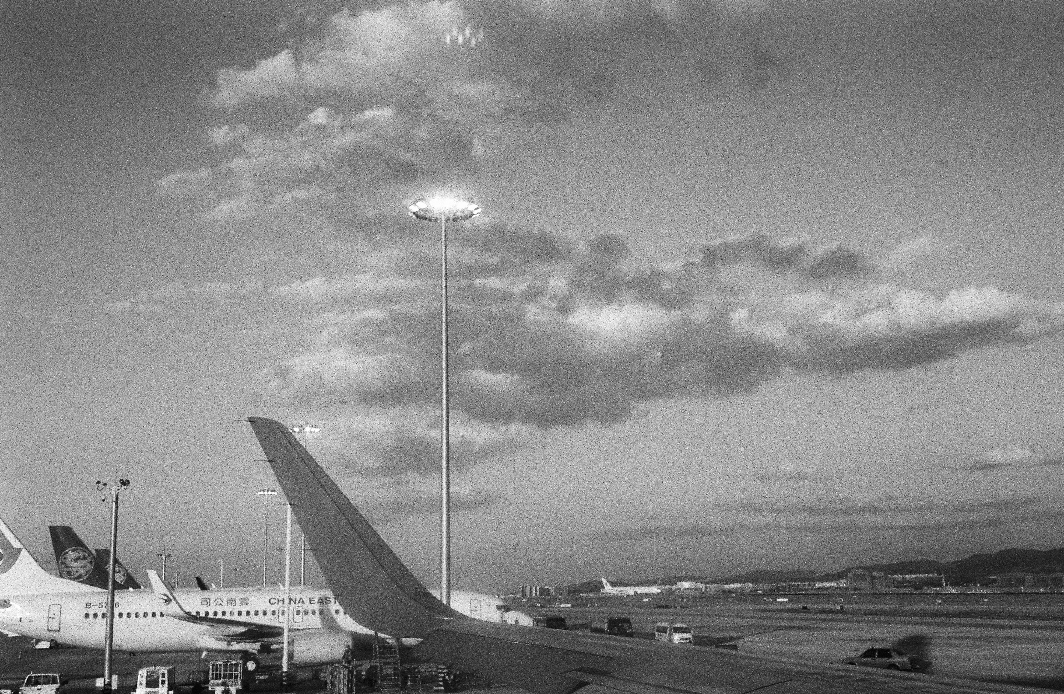 Airplanes parked at an airport with cloudy sky.