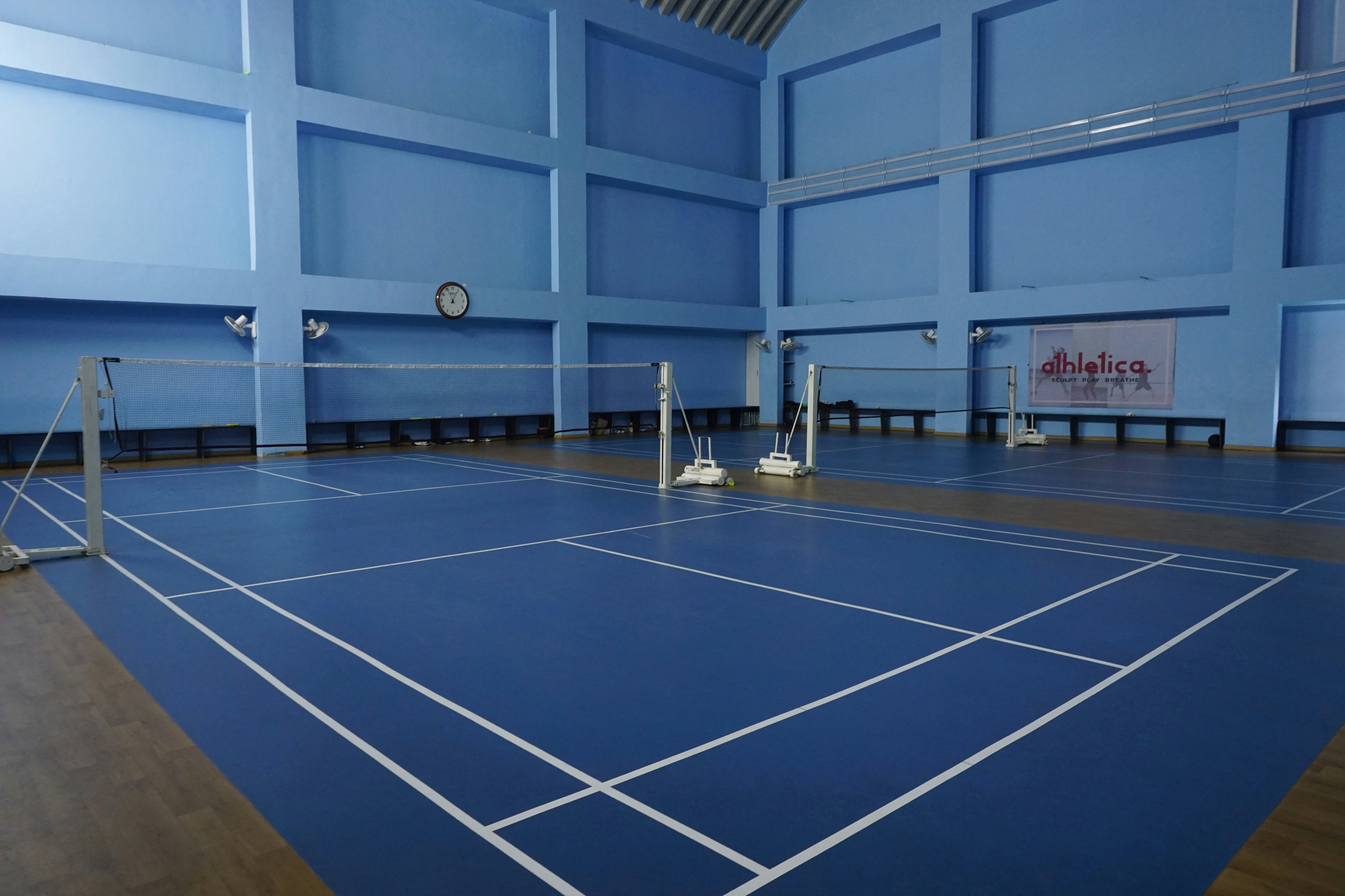 Pistas de bádminton cubiertas vacías con suelo azul.
