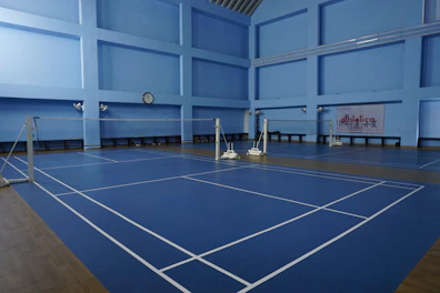 Empty indoor badminton courts with blue flooring