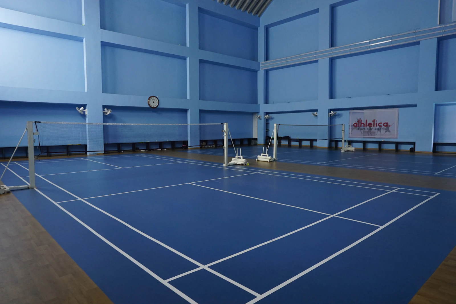 Empty indoor sports court with blue flooring and marked lines, no players in frame