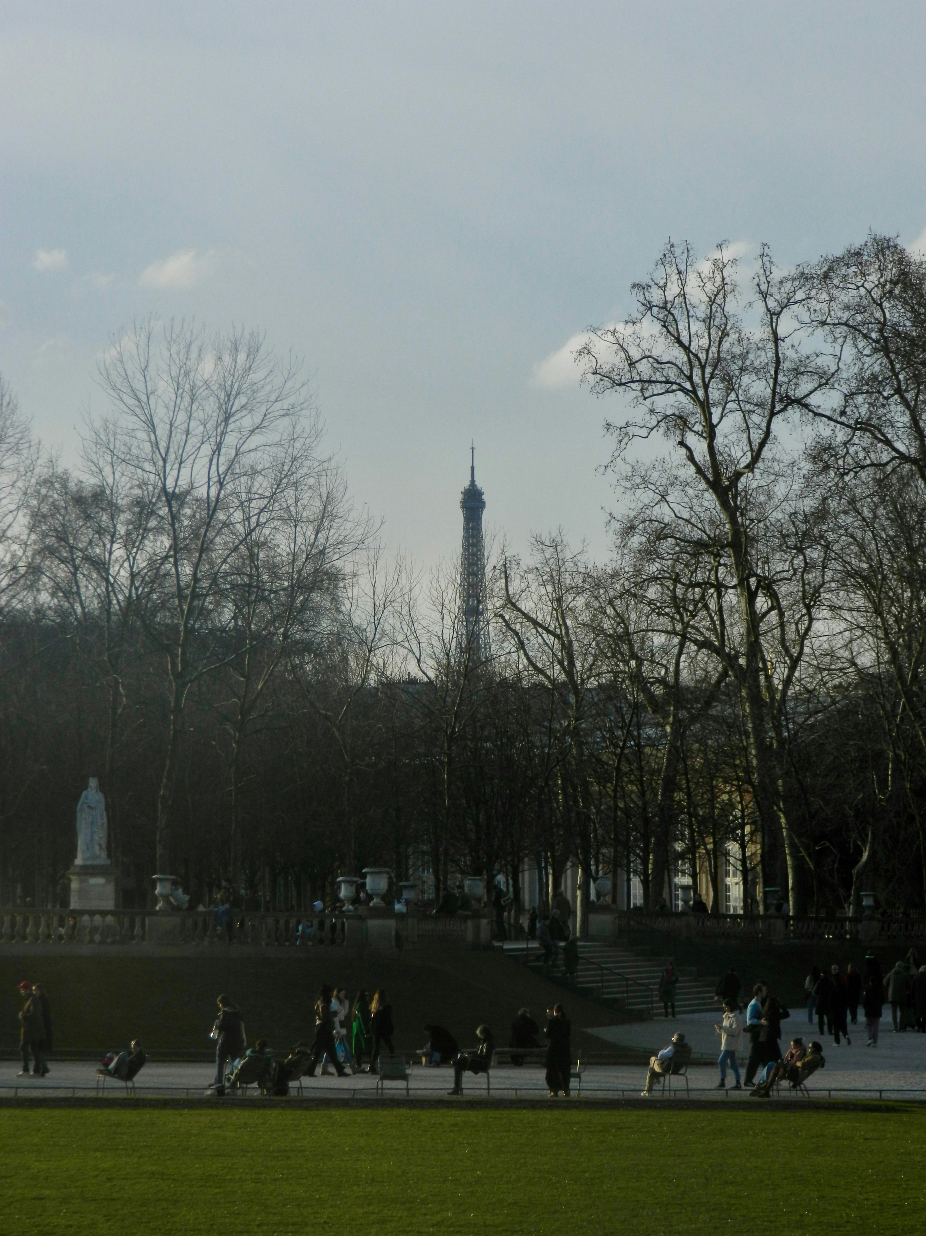 Torre Eiffel visibile sopra gli alberi del parco con persone che passeggiano