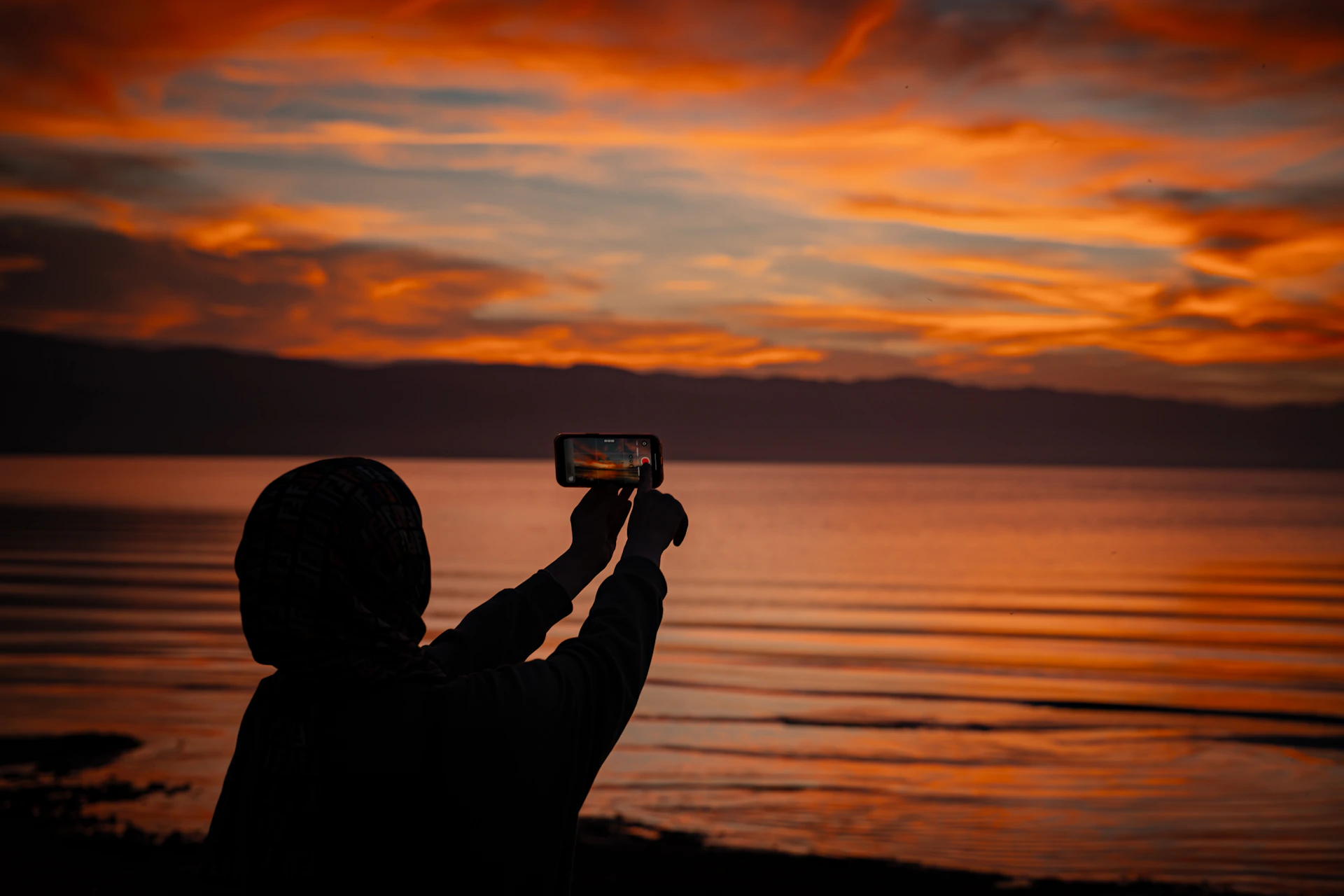 Person taking a selfie by the ocean at sunset