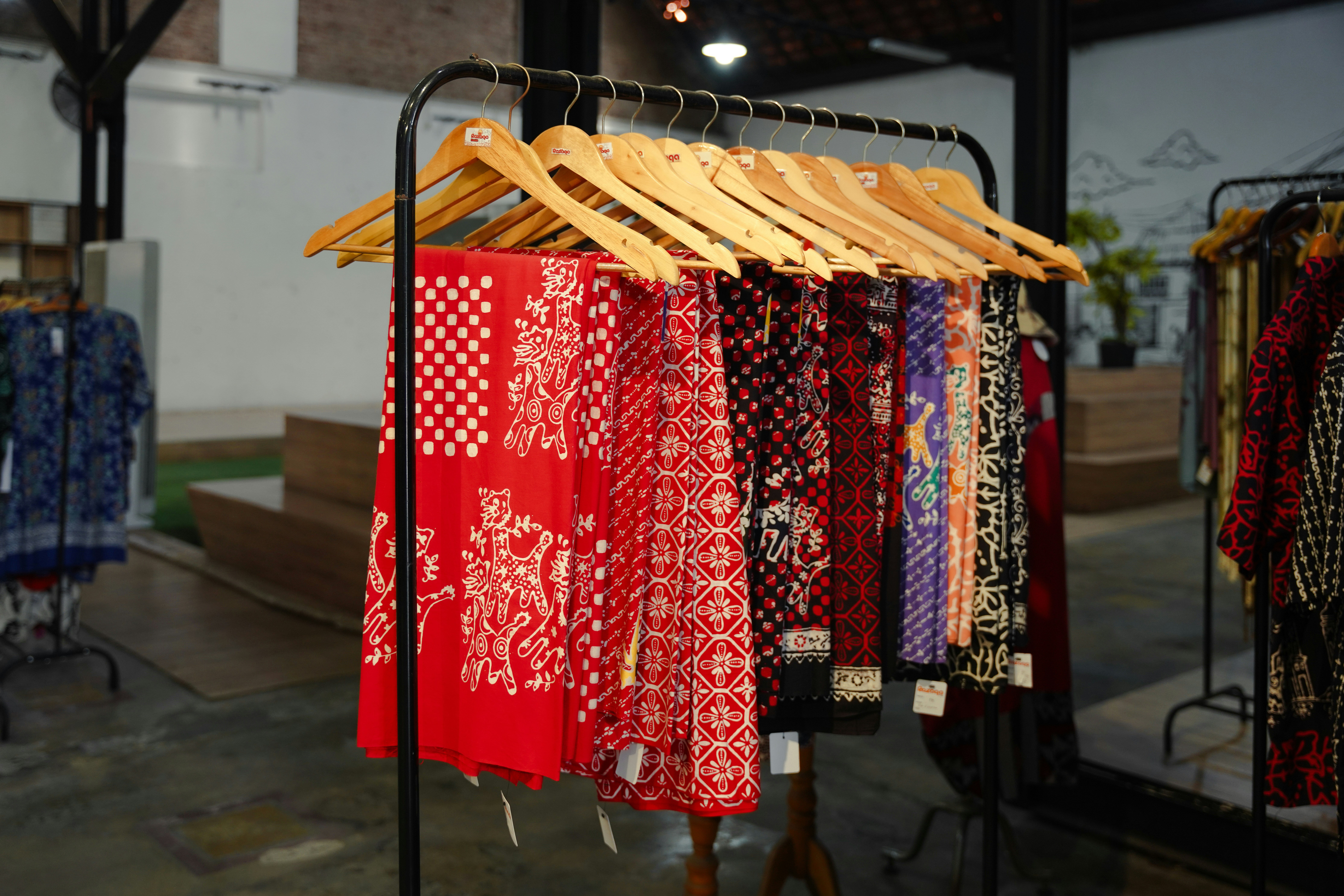 Colorful patterned fabrics hang on a rack.