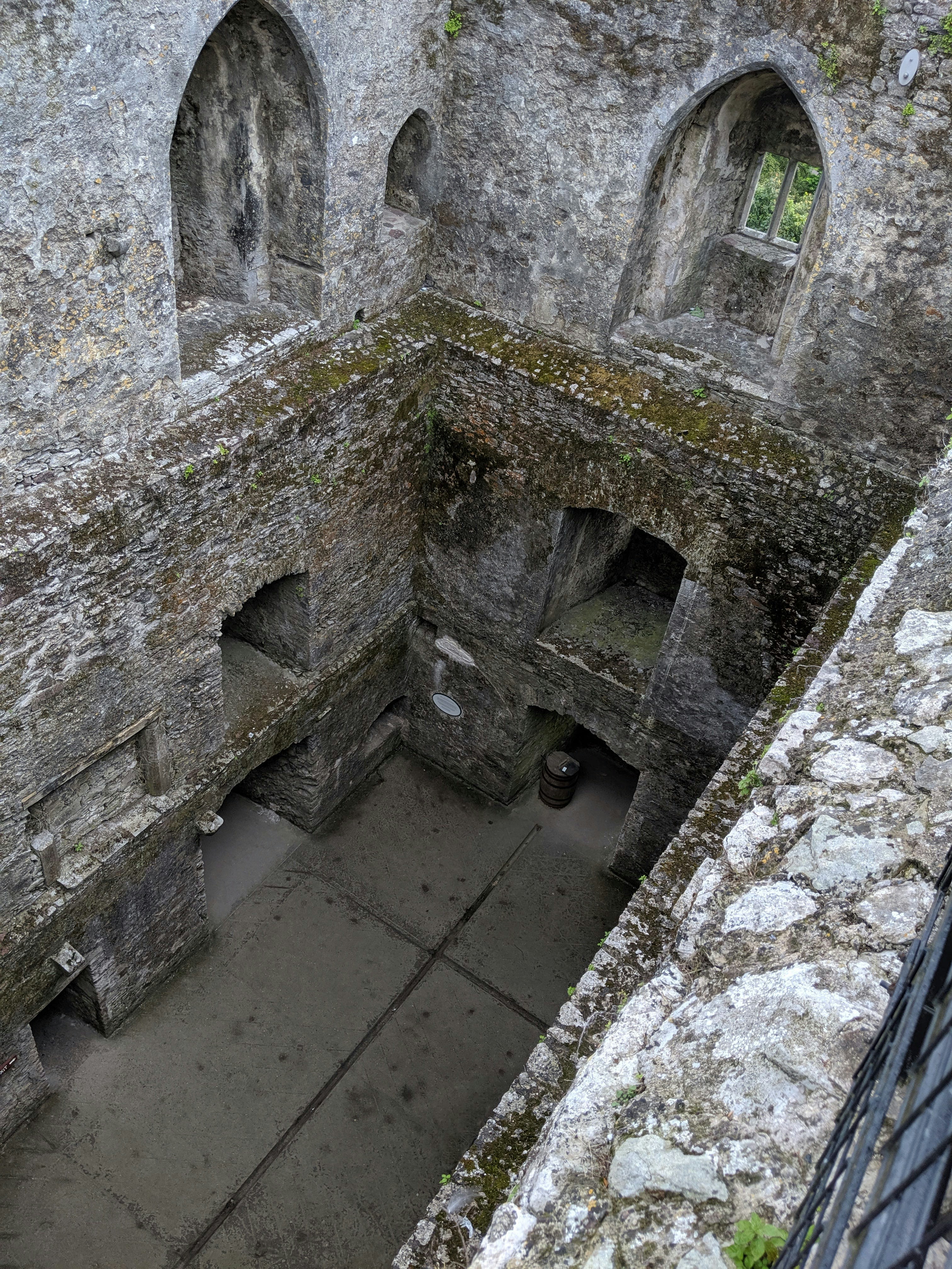 Intérieur d’une ruine de château en pierre avec des fenêtres en arc.