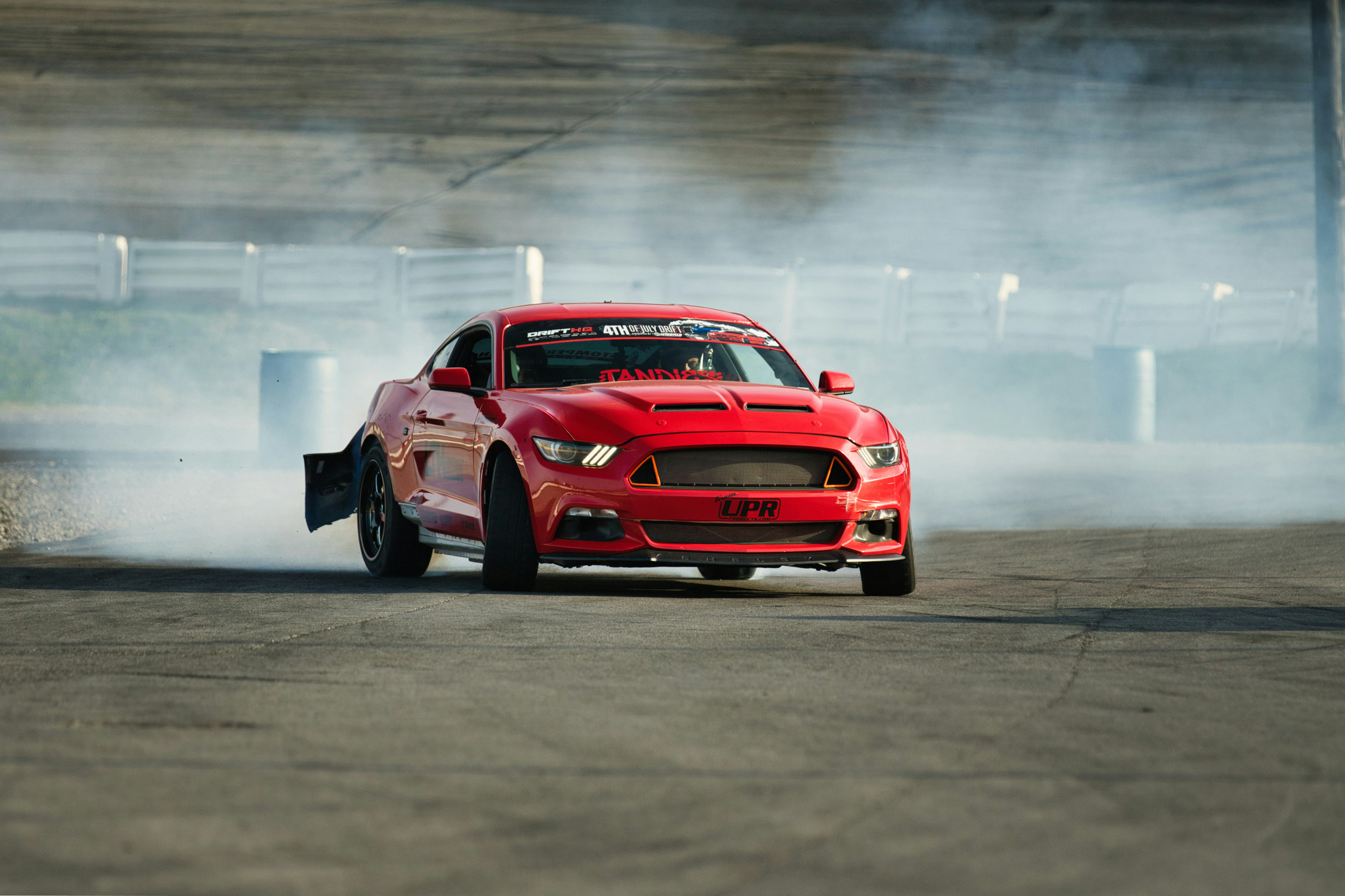 Coche deportivo rojo derrape en pista con humo