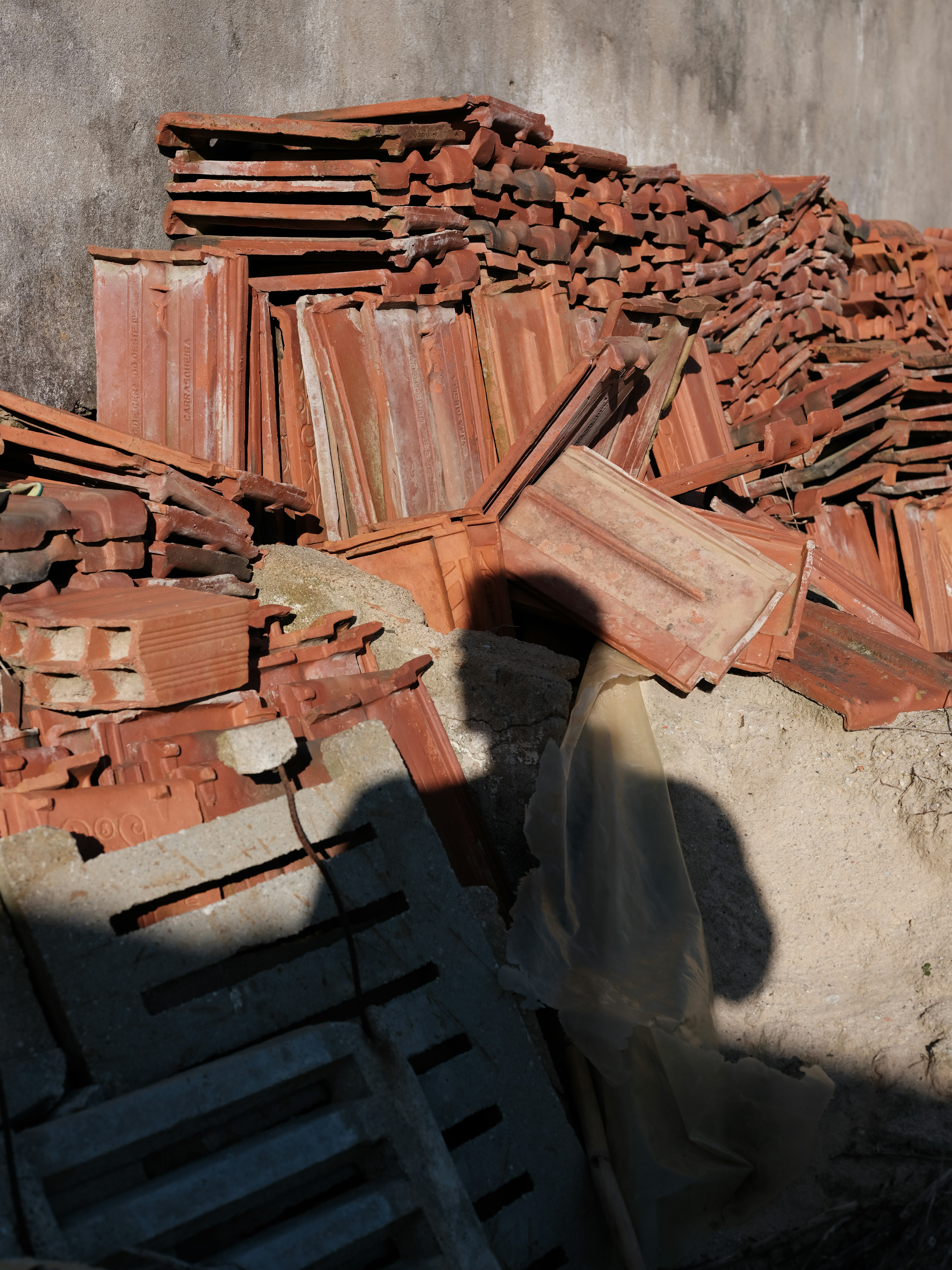 Pile of terracotta roof tiles stacked outdoors