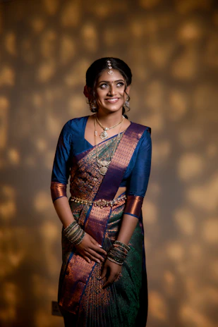 A woman in a blue and purple sari smiles.