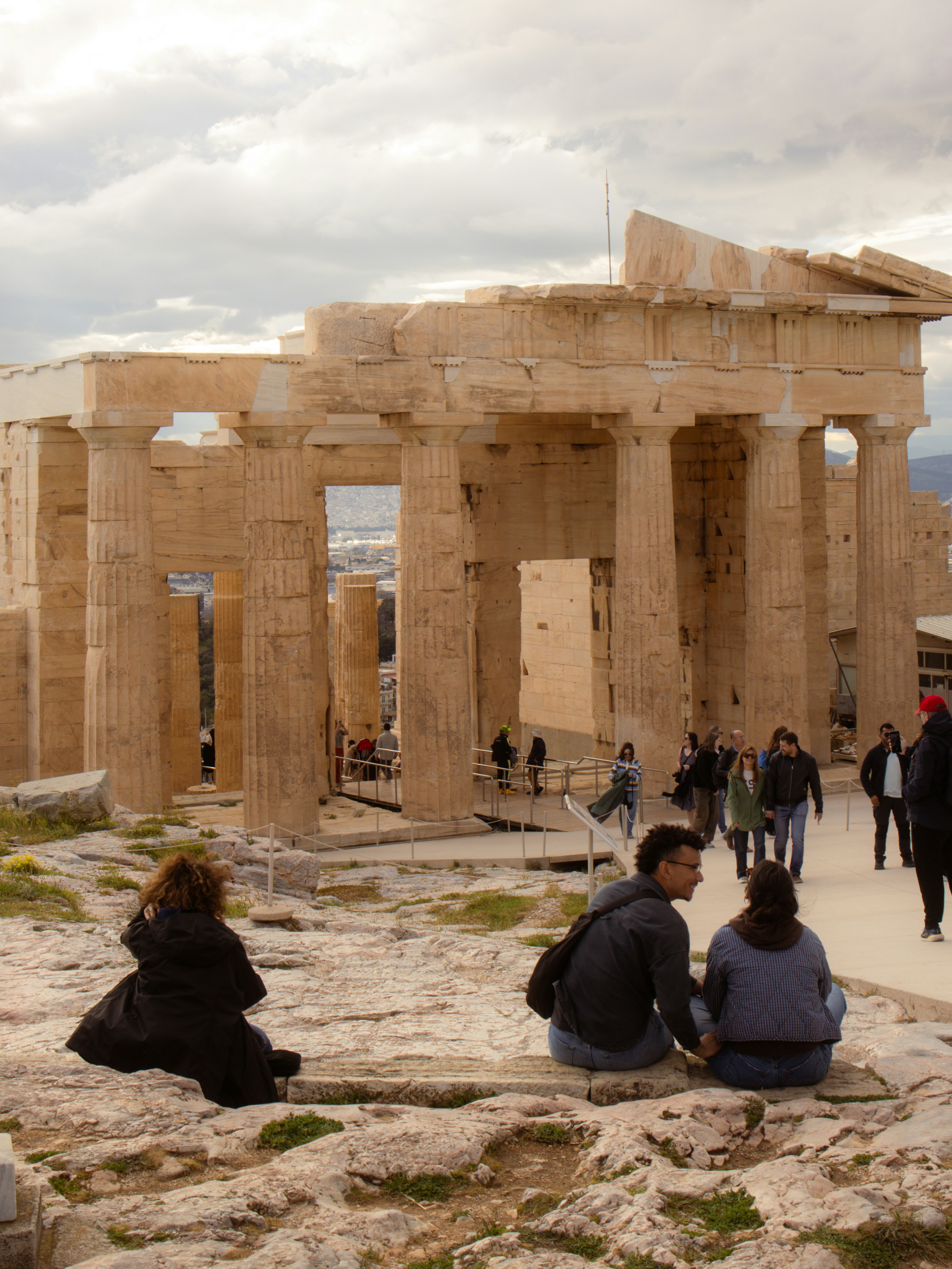 People sitting on rocks near ancient greek ruins