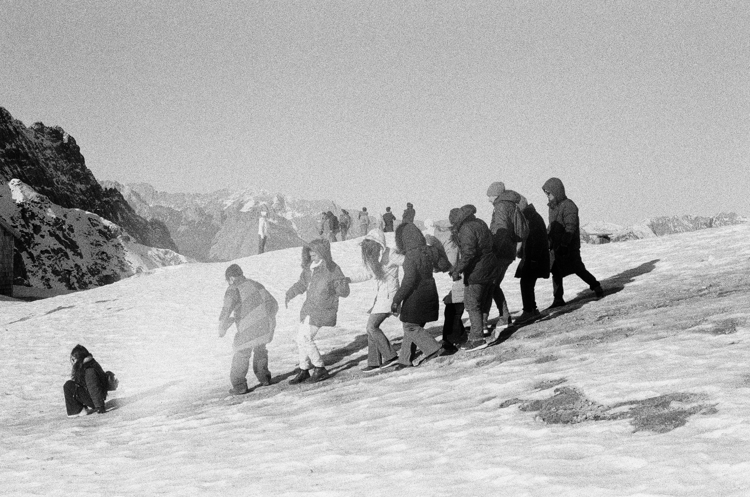 Grupo de pessoas caminhando por uma encosta nevada da montanha.