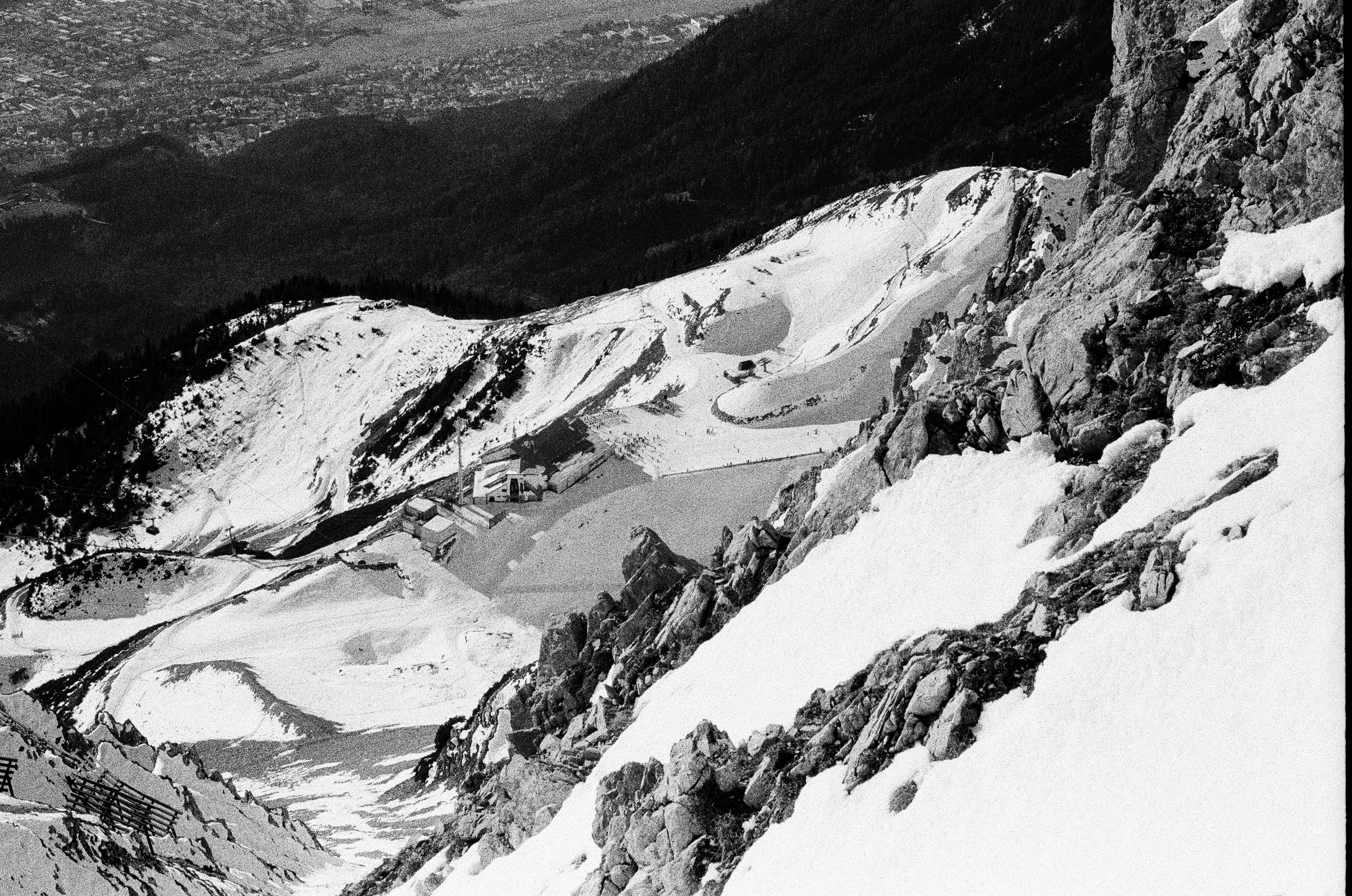 Encostas montanhosas nevadas com afloramentos rochosos e áreas áridas.
