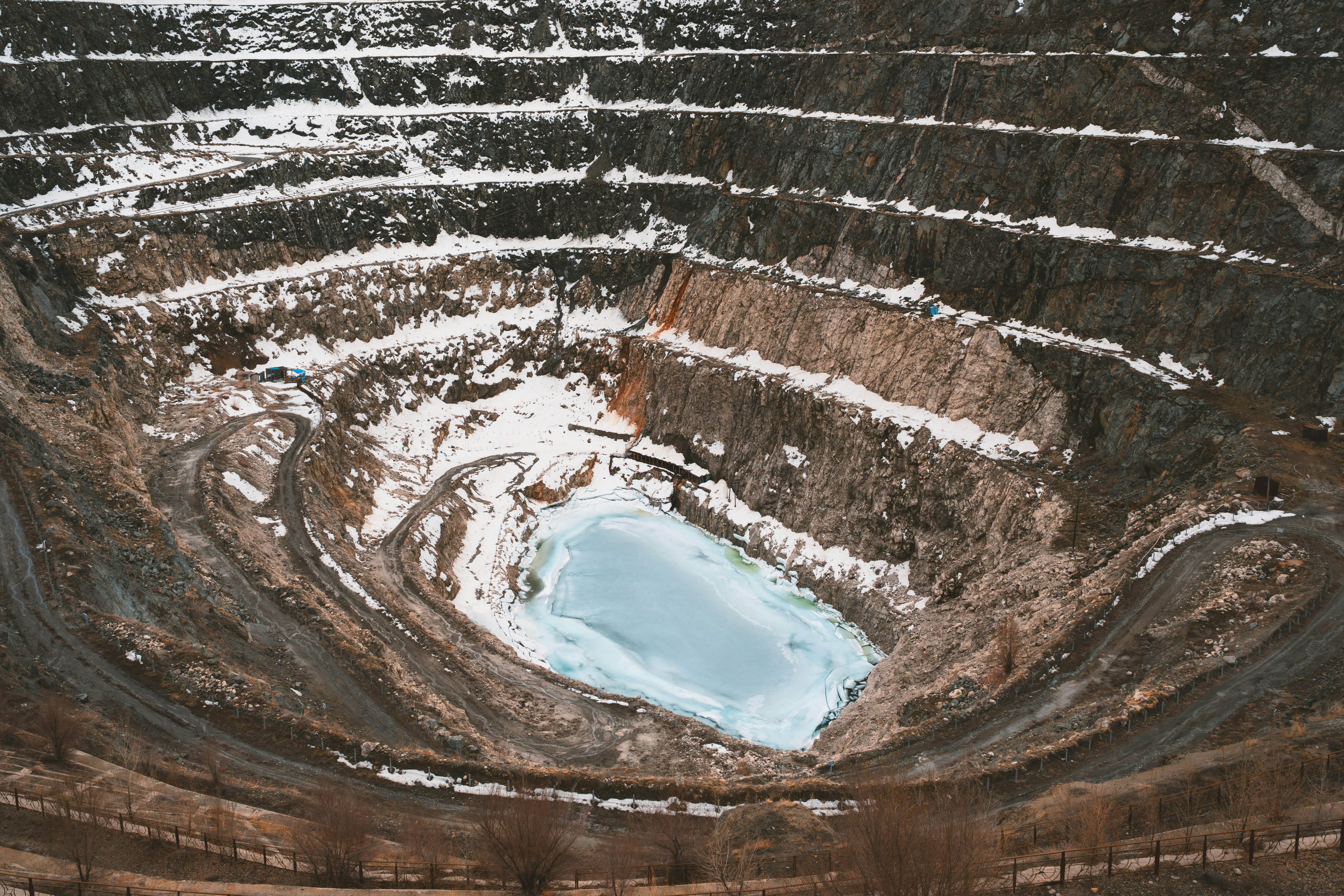 Aerial view of a large open-pit mine with water.