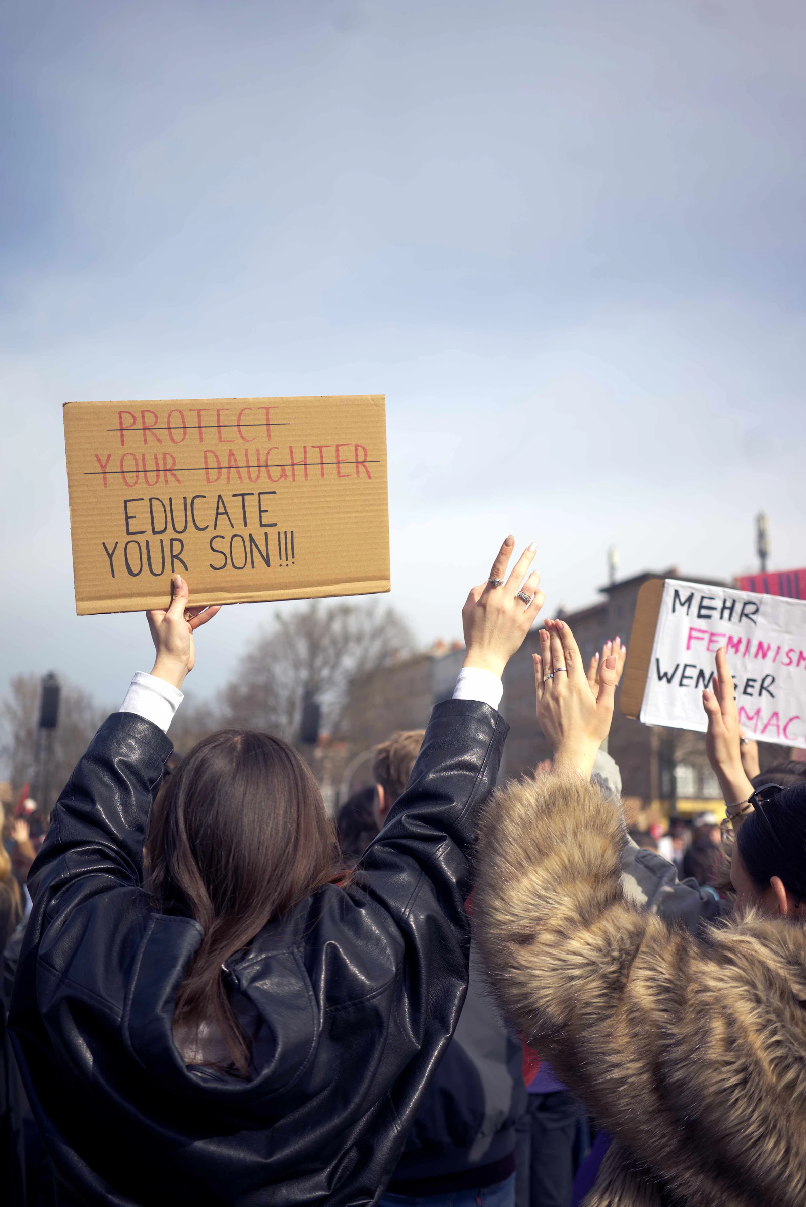 A crowd holding protest signs in a peaceful rally, suggesting values-led activism