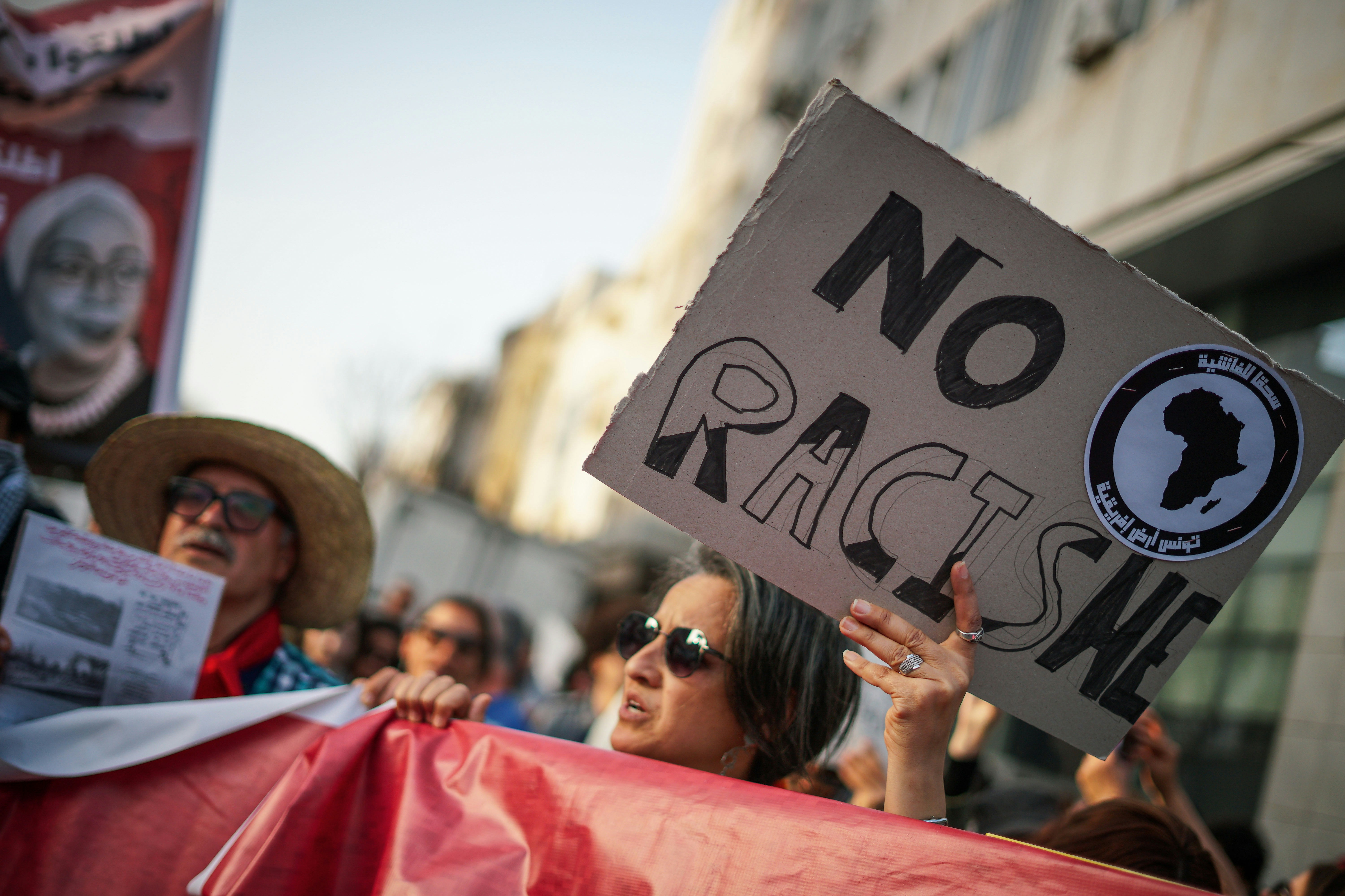 People protest with a "no racism" sign.