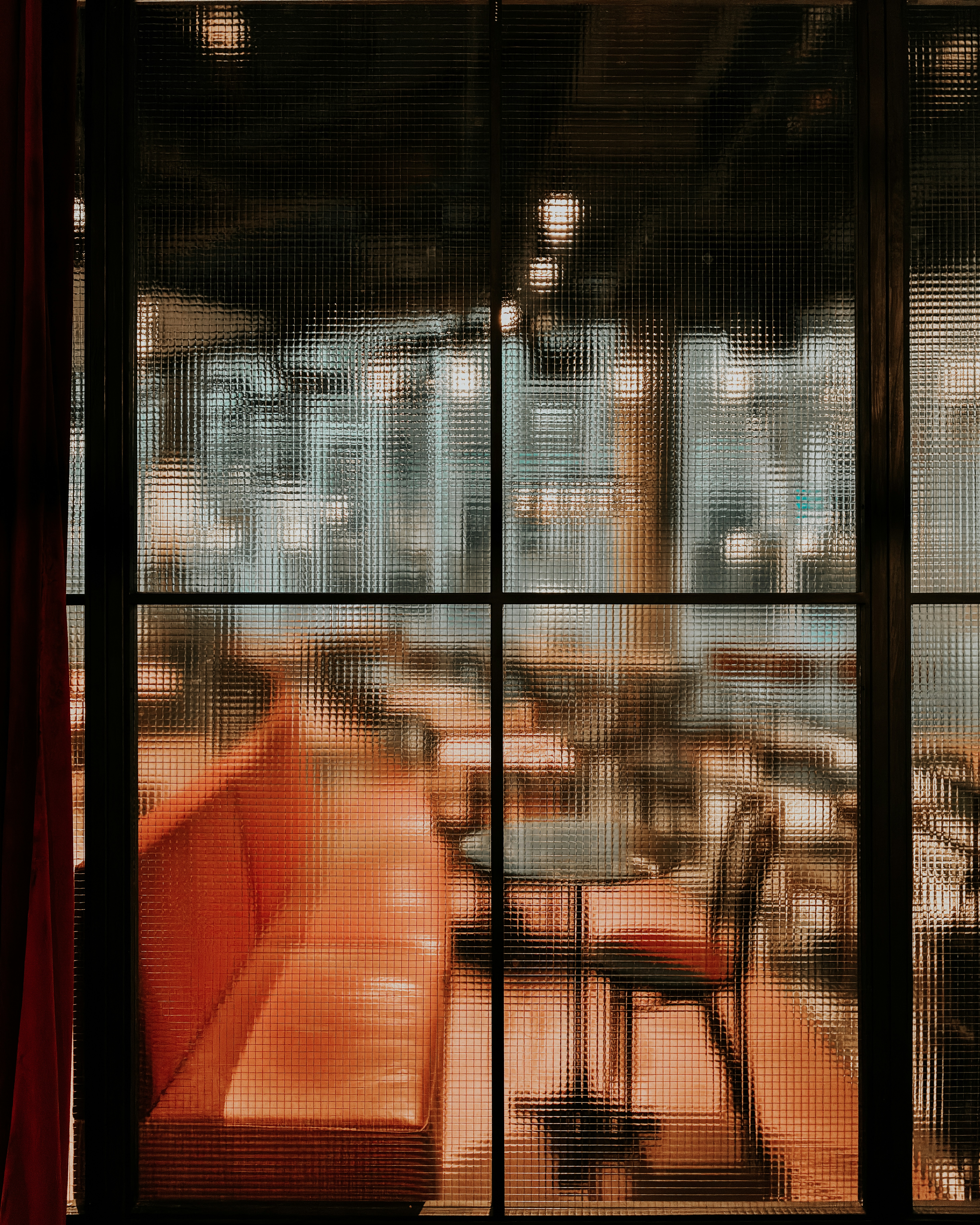 Orange booth and chairs seen through a textured window.