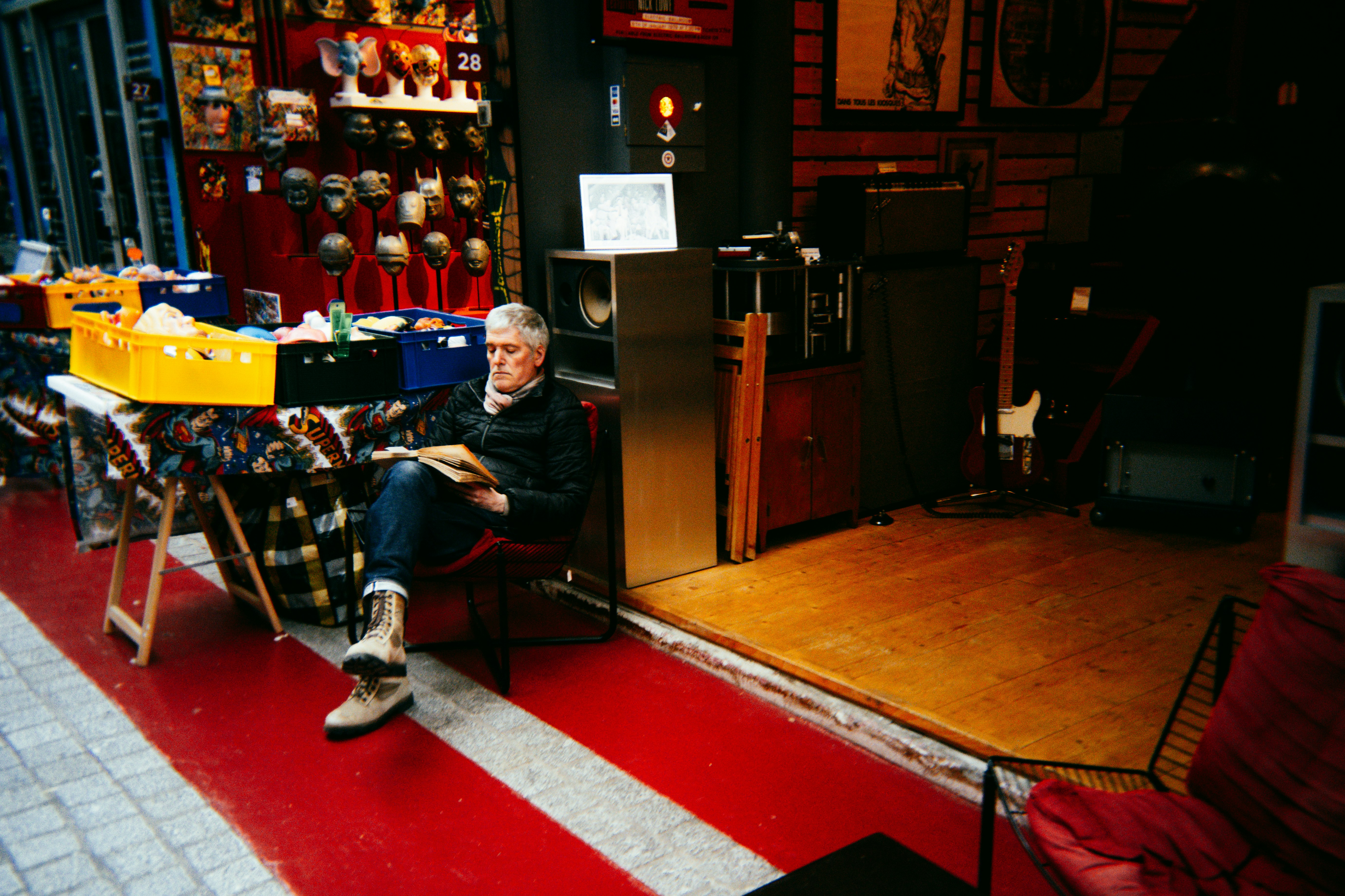 Man sitting in a cluttered shop reading a book