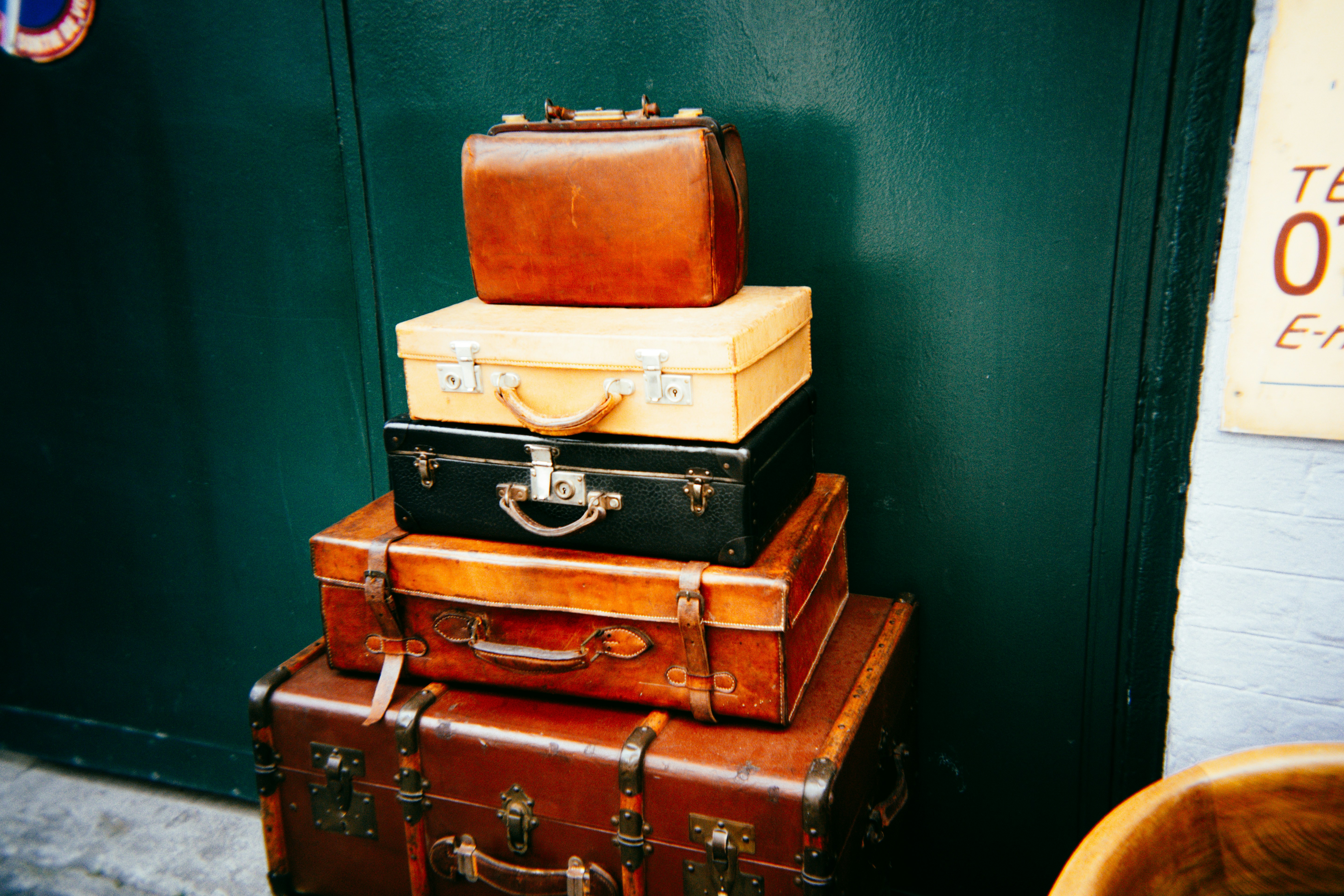 Stack of vintage suitcases against a dark green wall.