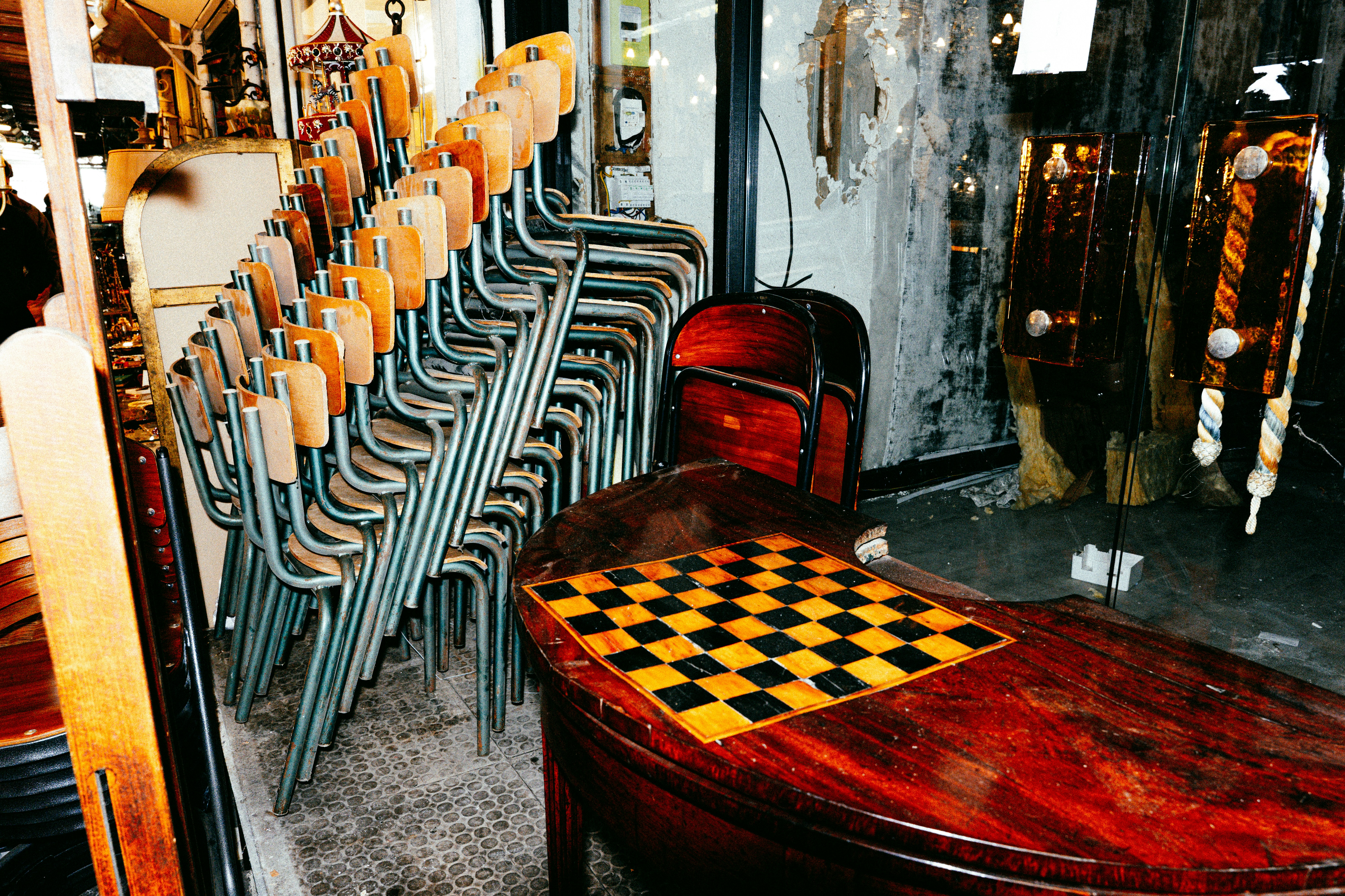 Ein Stapel Stühle neben einem Holztisch mit Schachbrett