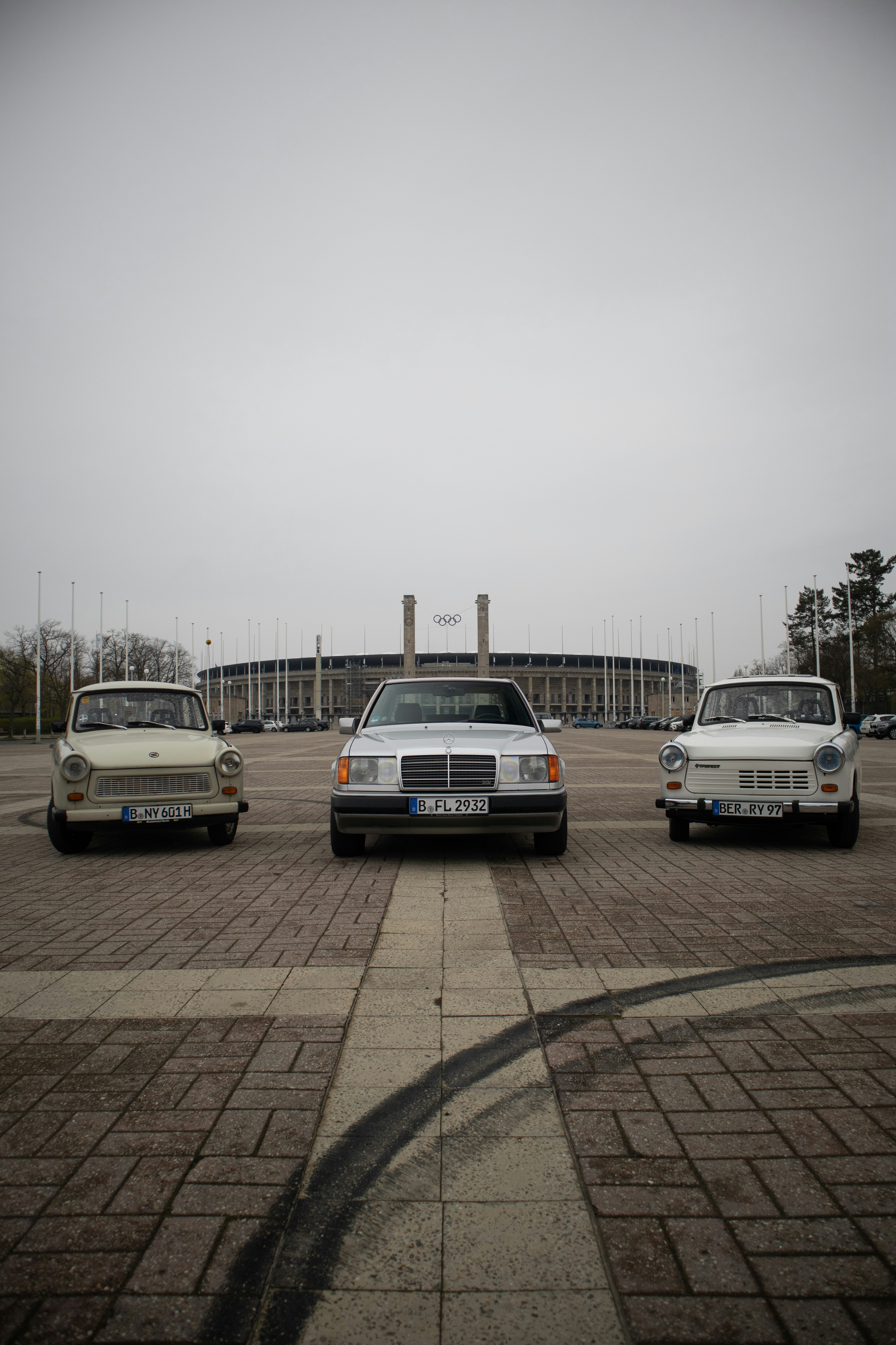 Three vintage cars parked in front of stadium