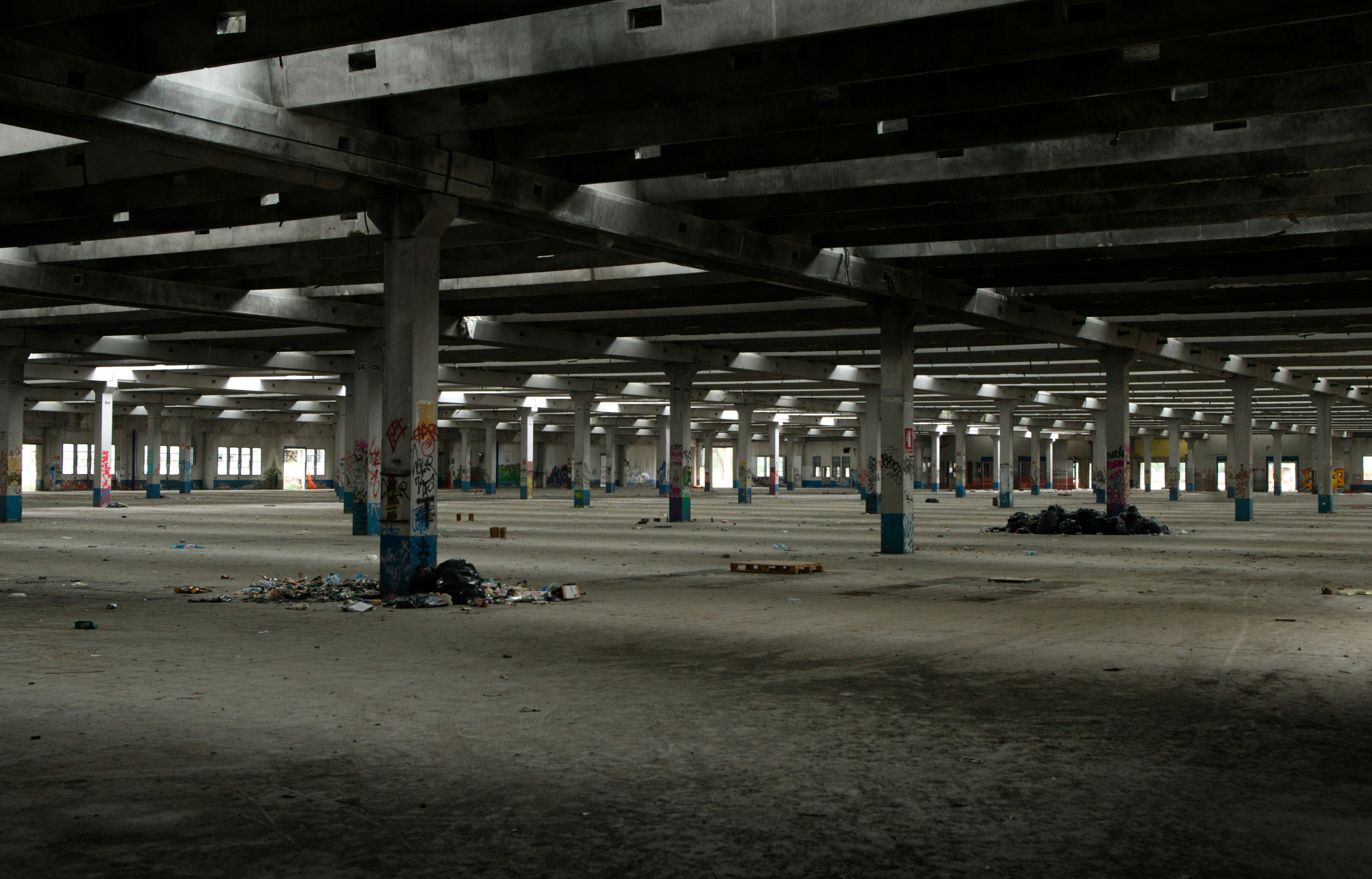 Vast, empty industrial warehouse with concrete columns.