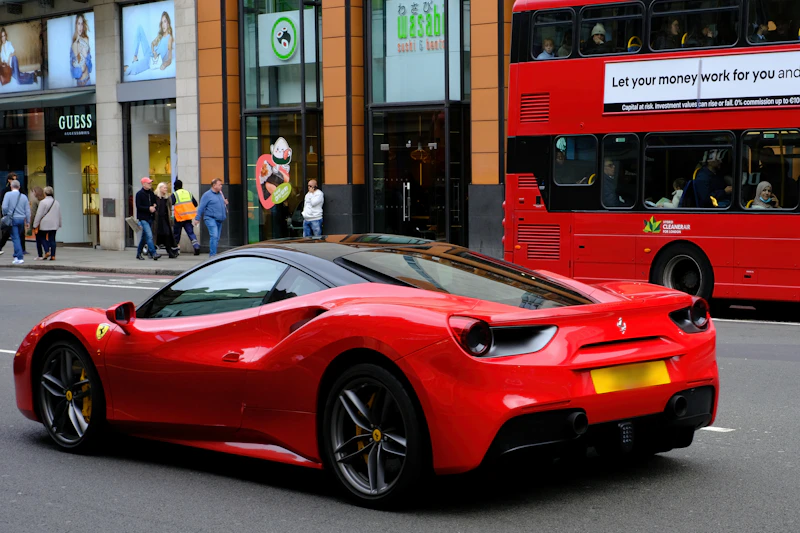 Coche deportivo rojo conduciendo por una calle de la ciudad