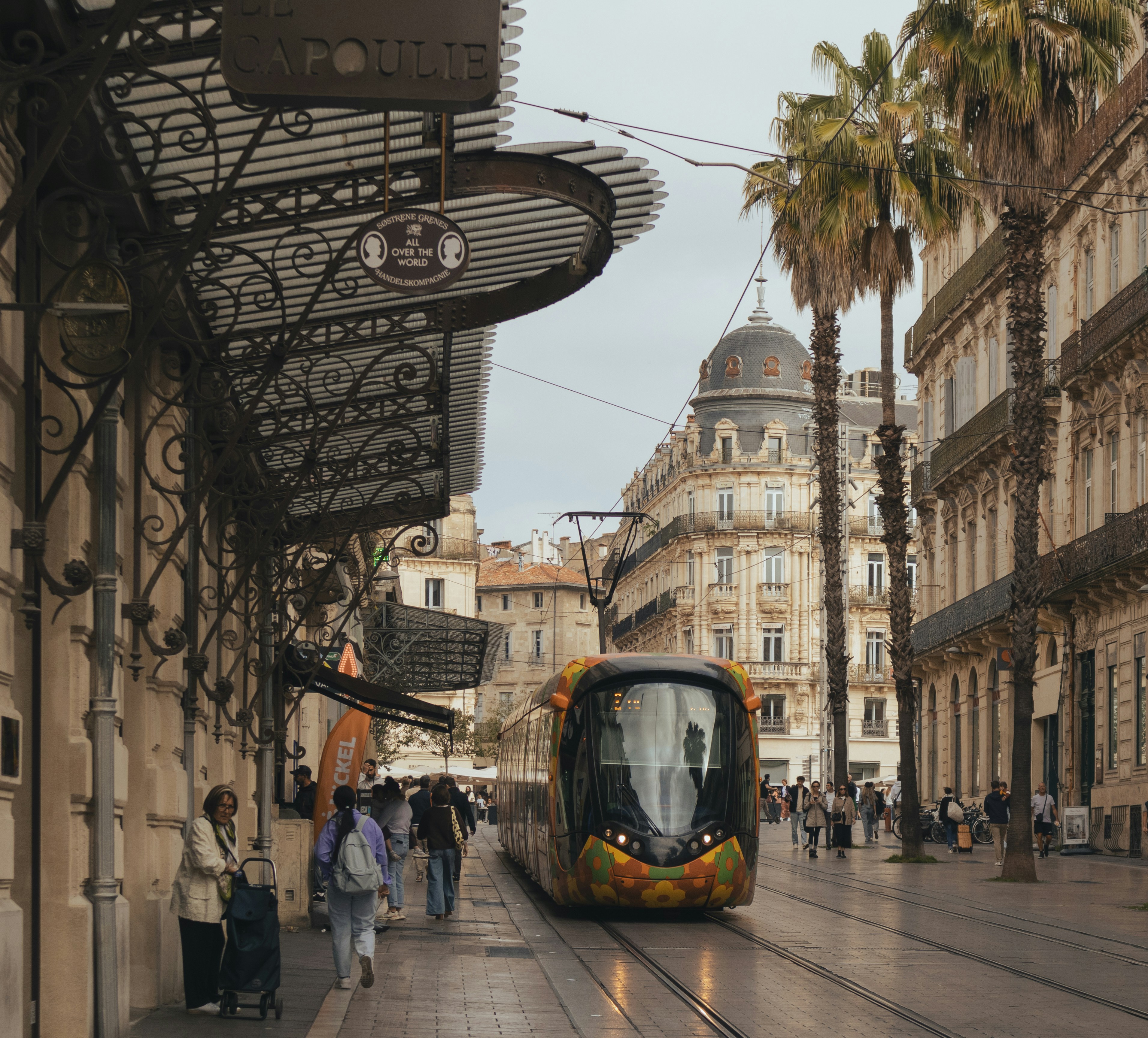 Eine moderne Straßenbahn fährt eine historische europäische Straße entlang.