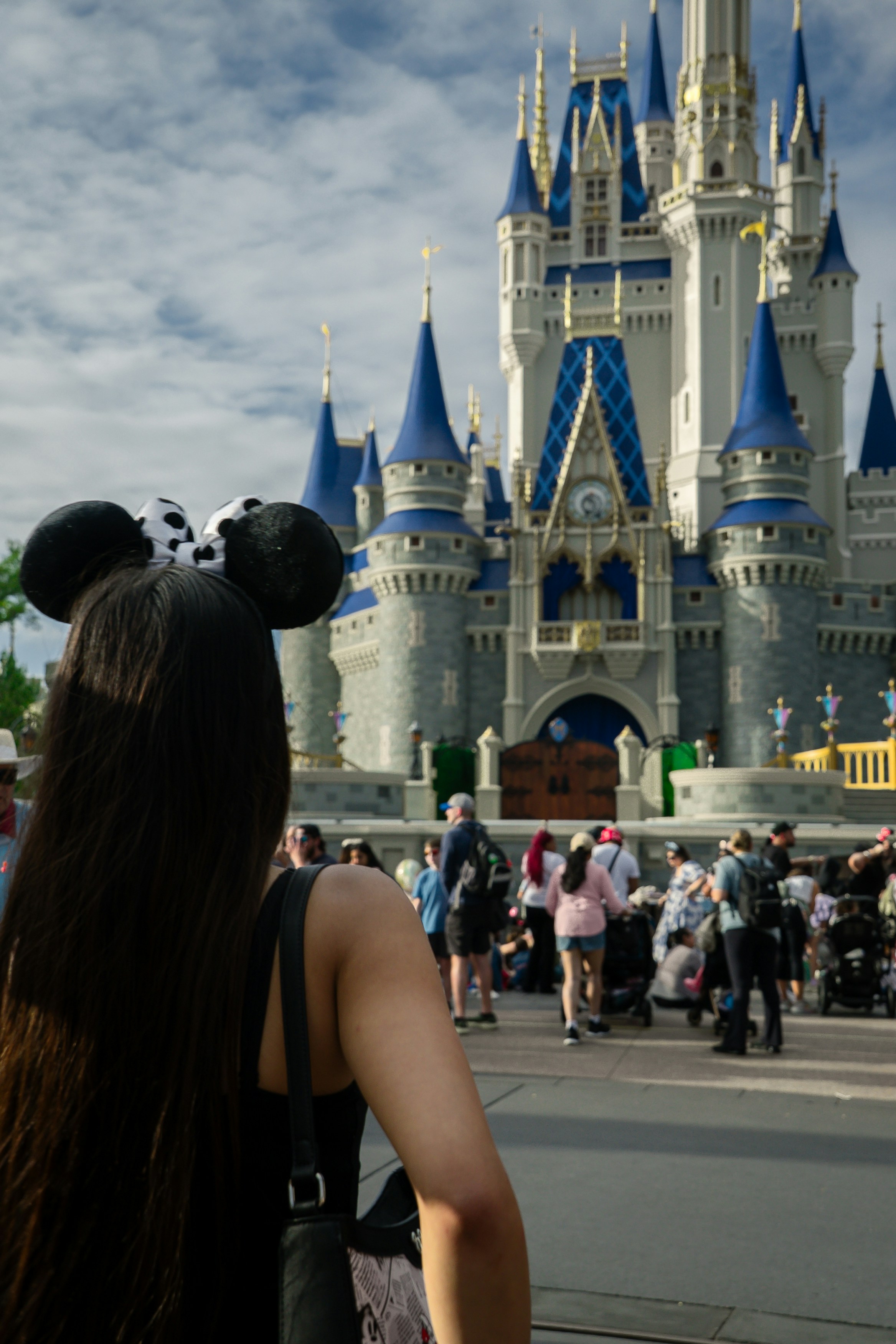 Woman with mouse ears in front of cinderella castle