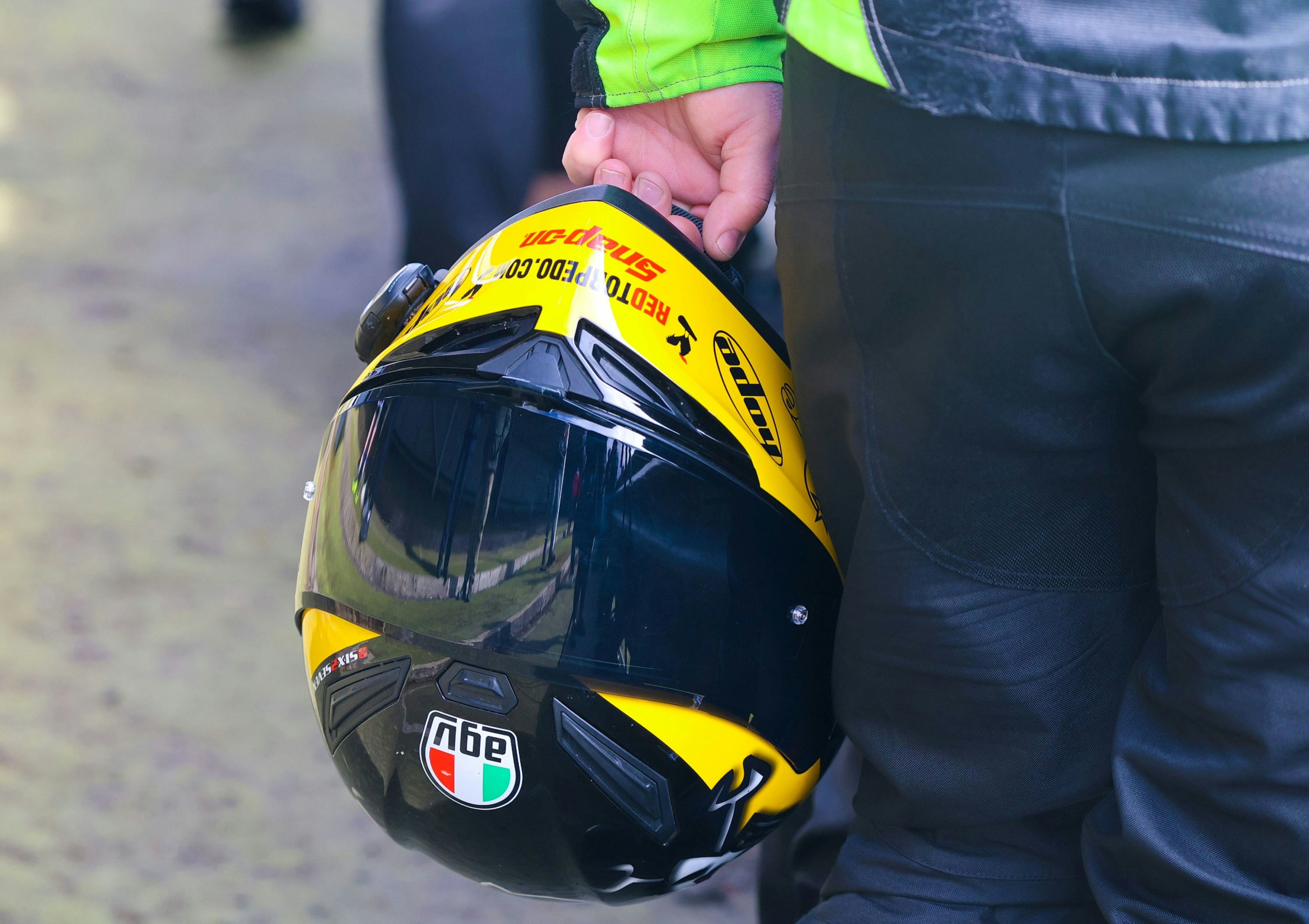 Person holding a yellow and black motorcycle helmet
