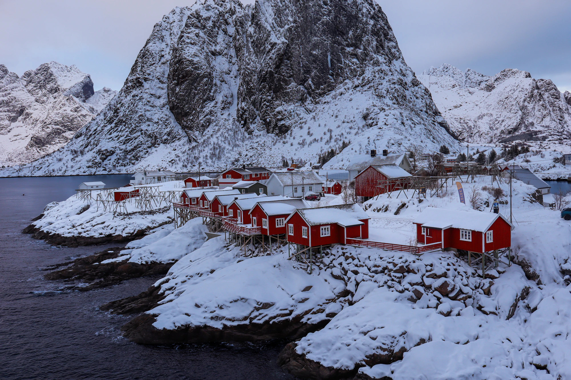 Vila costeira nas ilhas Lofoten cercada por montanhas nevadas