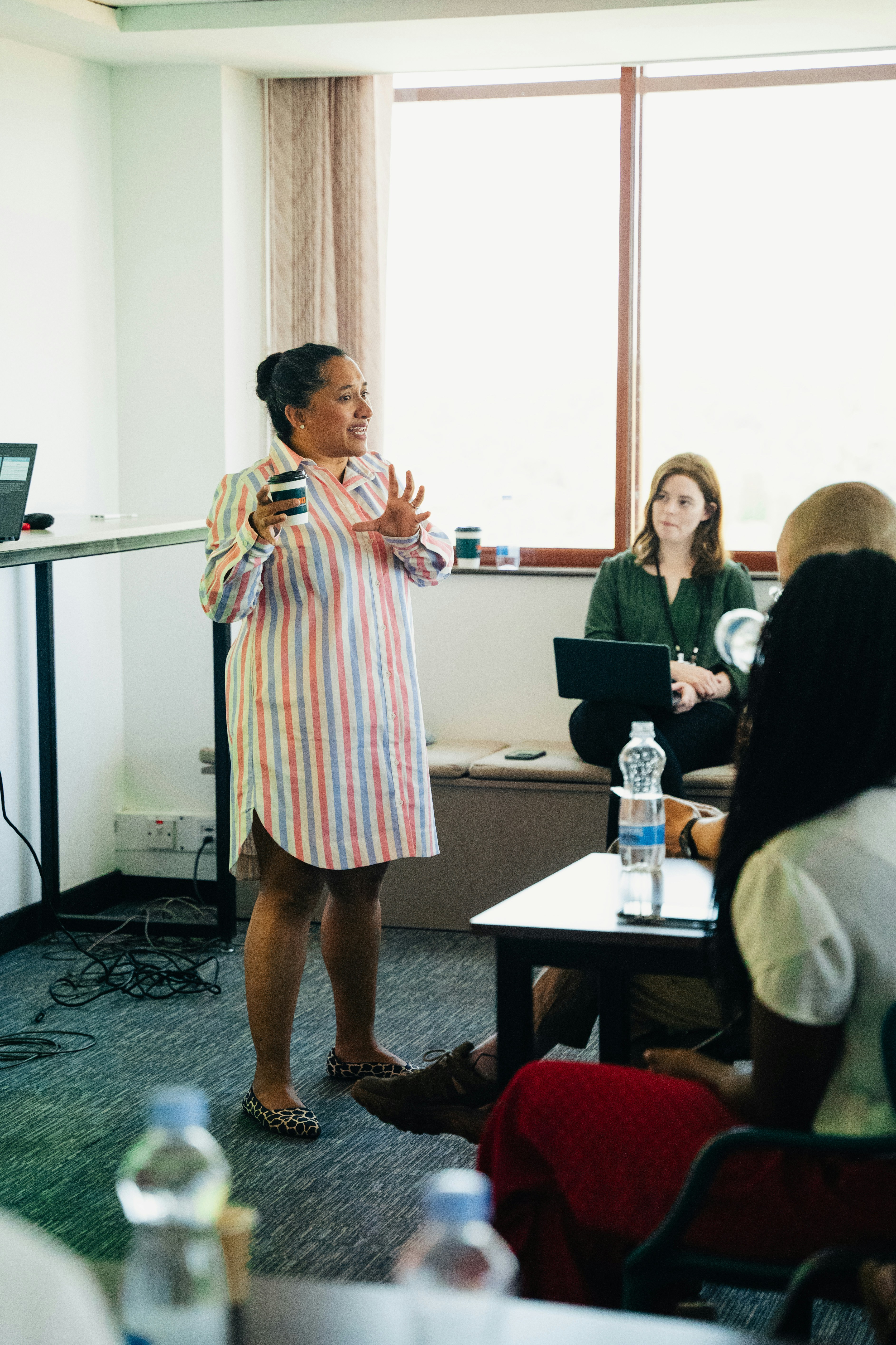Une femme présente devant un public dans une salle de réunion.