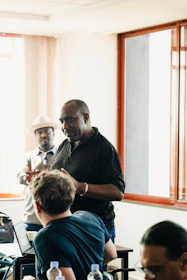 Men in a meeting room with laptops and water bottles.