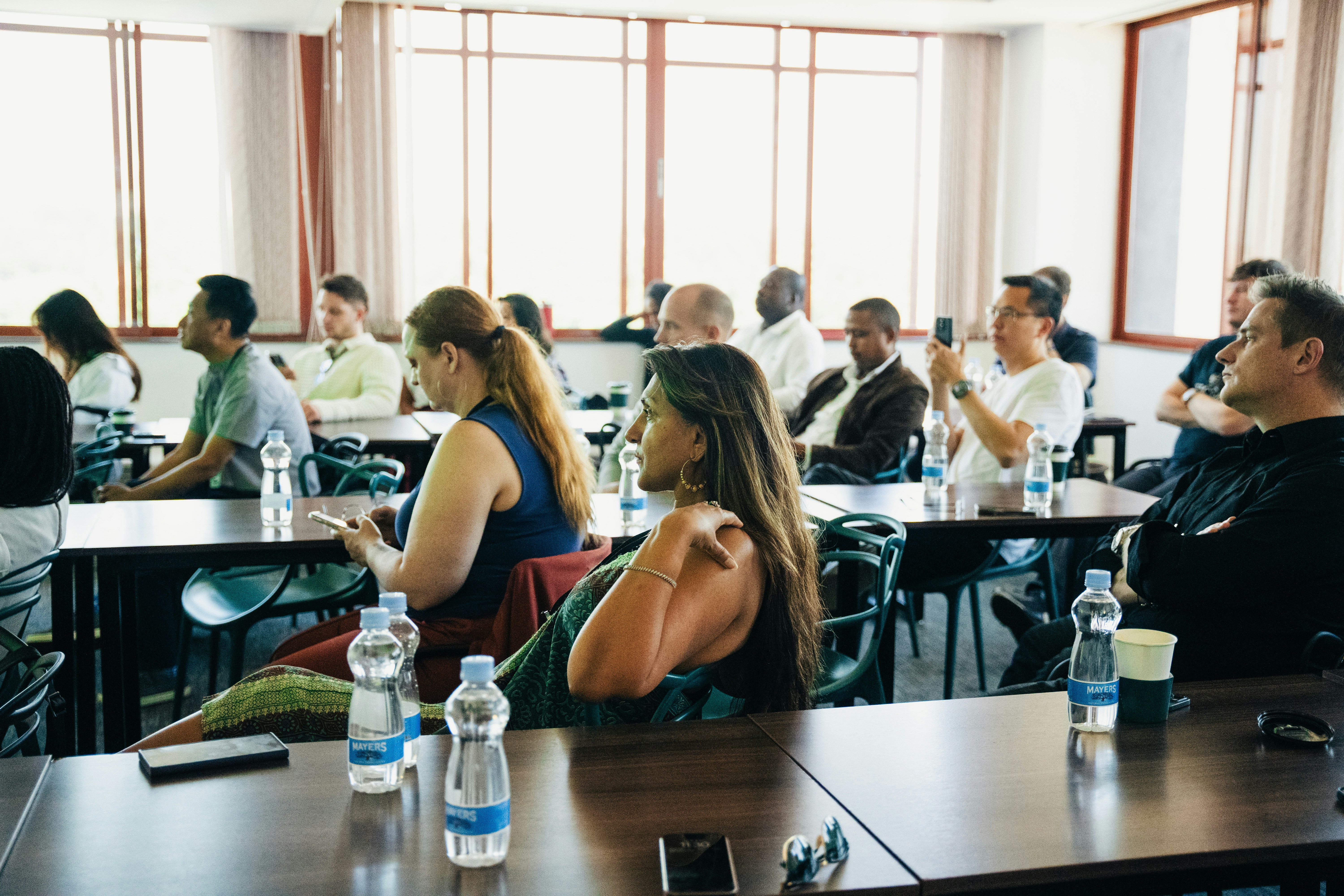 Des gens assis à des tables dans une salle de conférence.