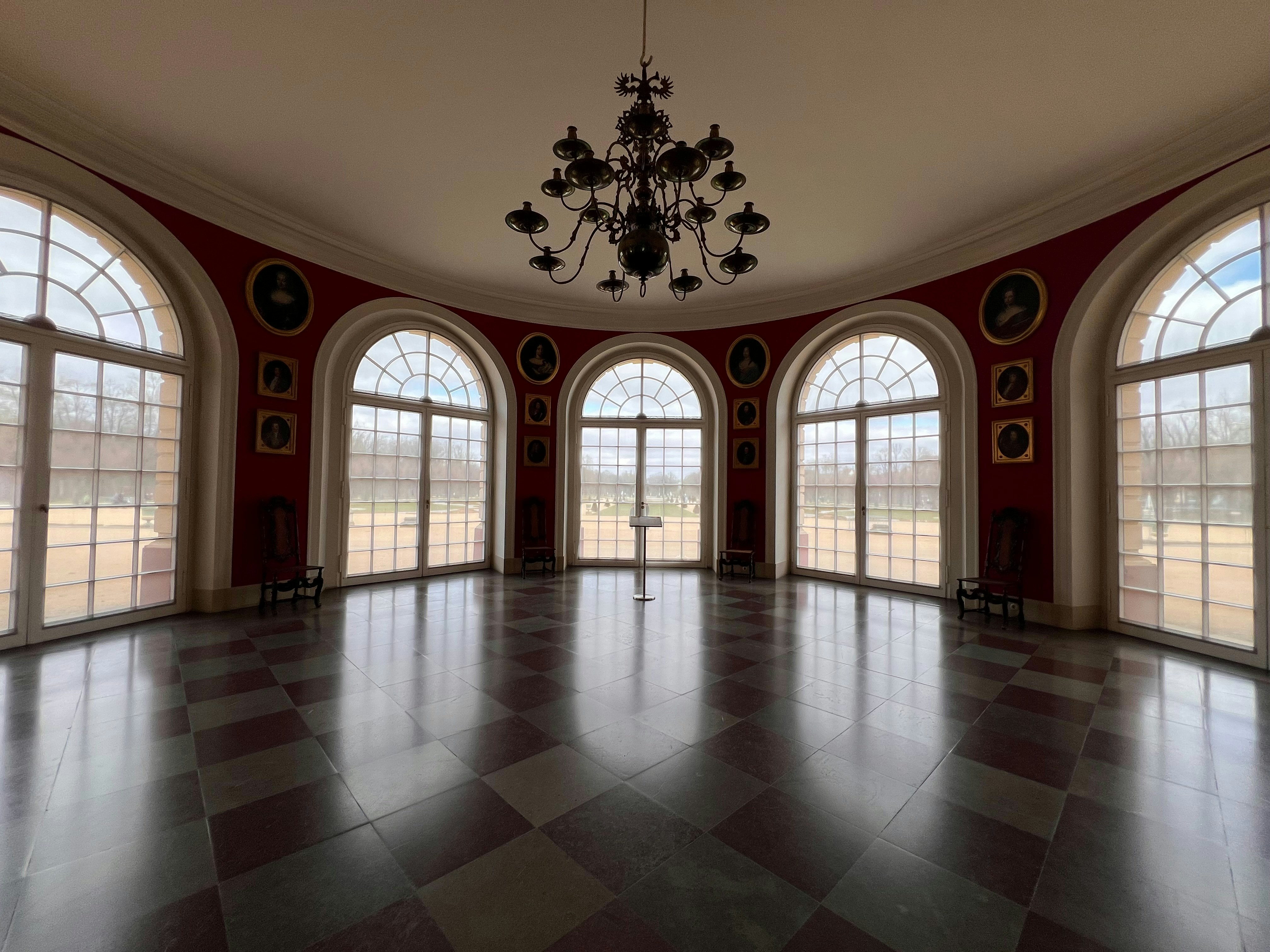 Elegant circular room with large arched windows and chandelier.