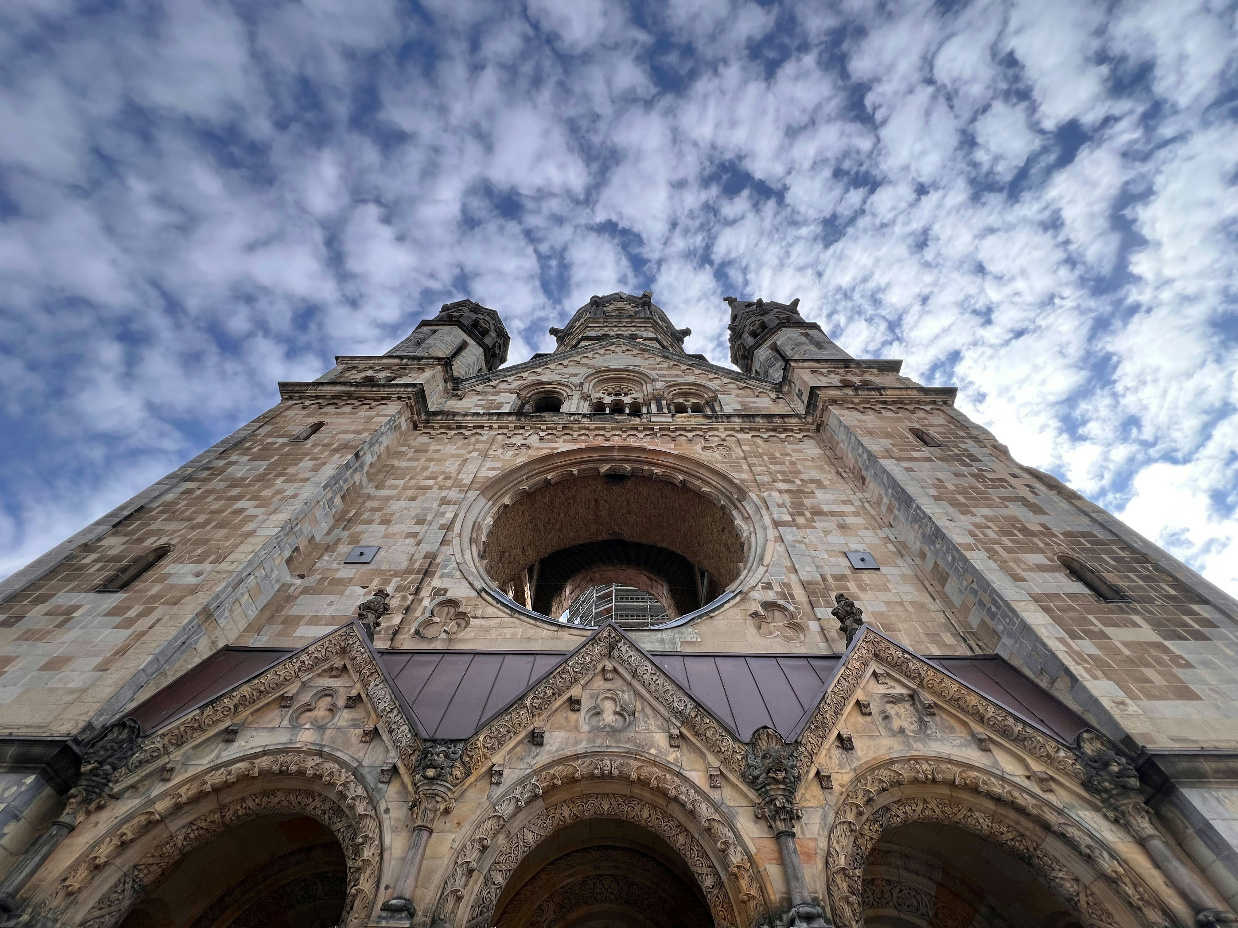 An ornate church facade viewed from below against clouds