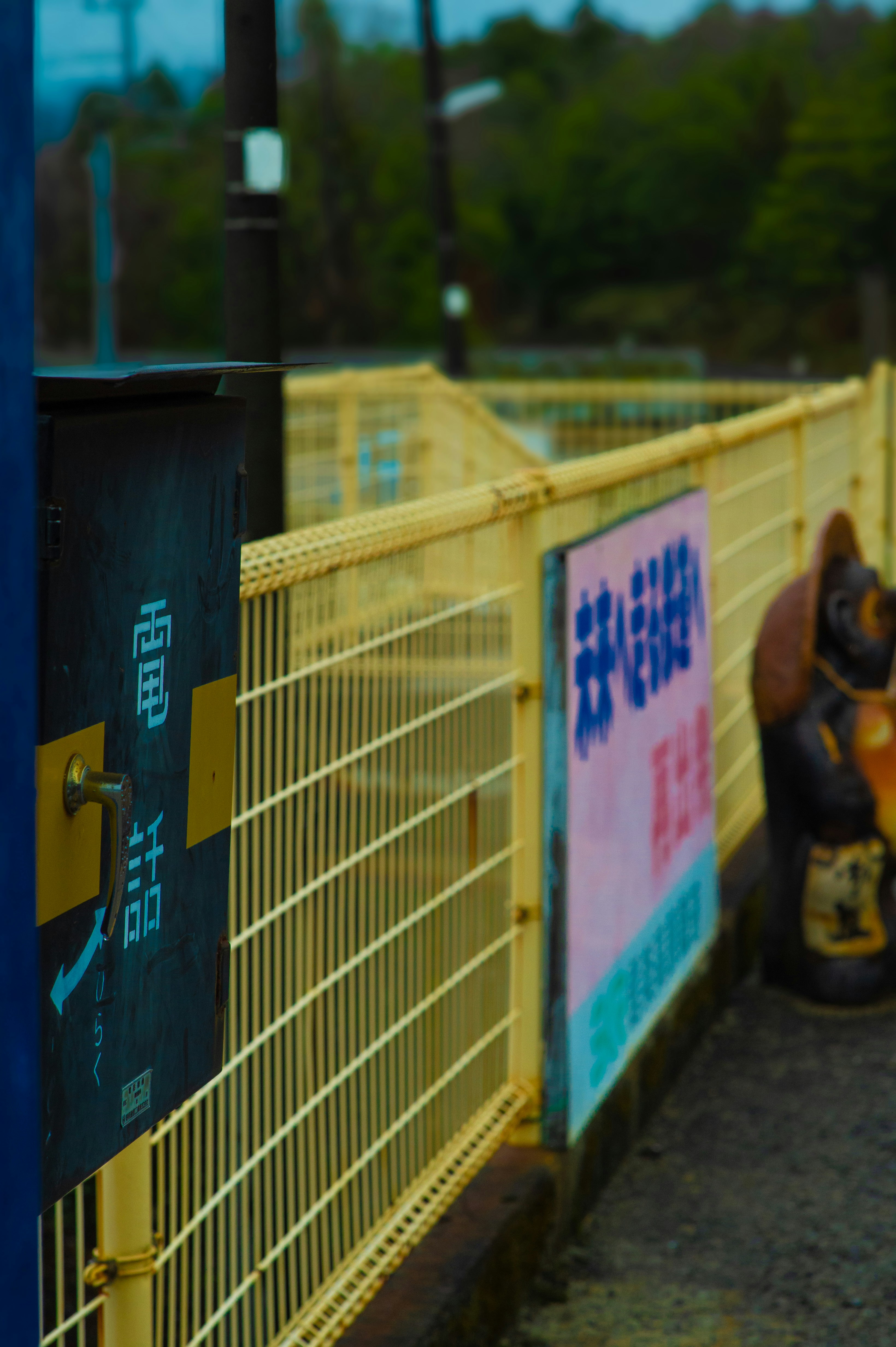 Yellow fence with japanese signs and statue