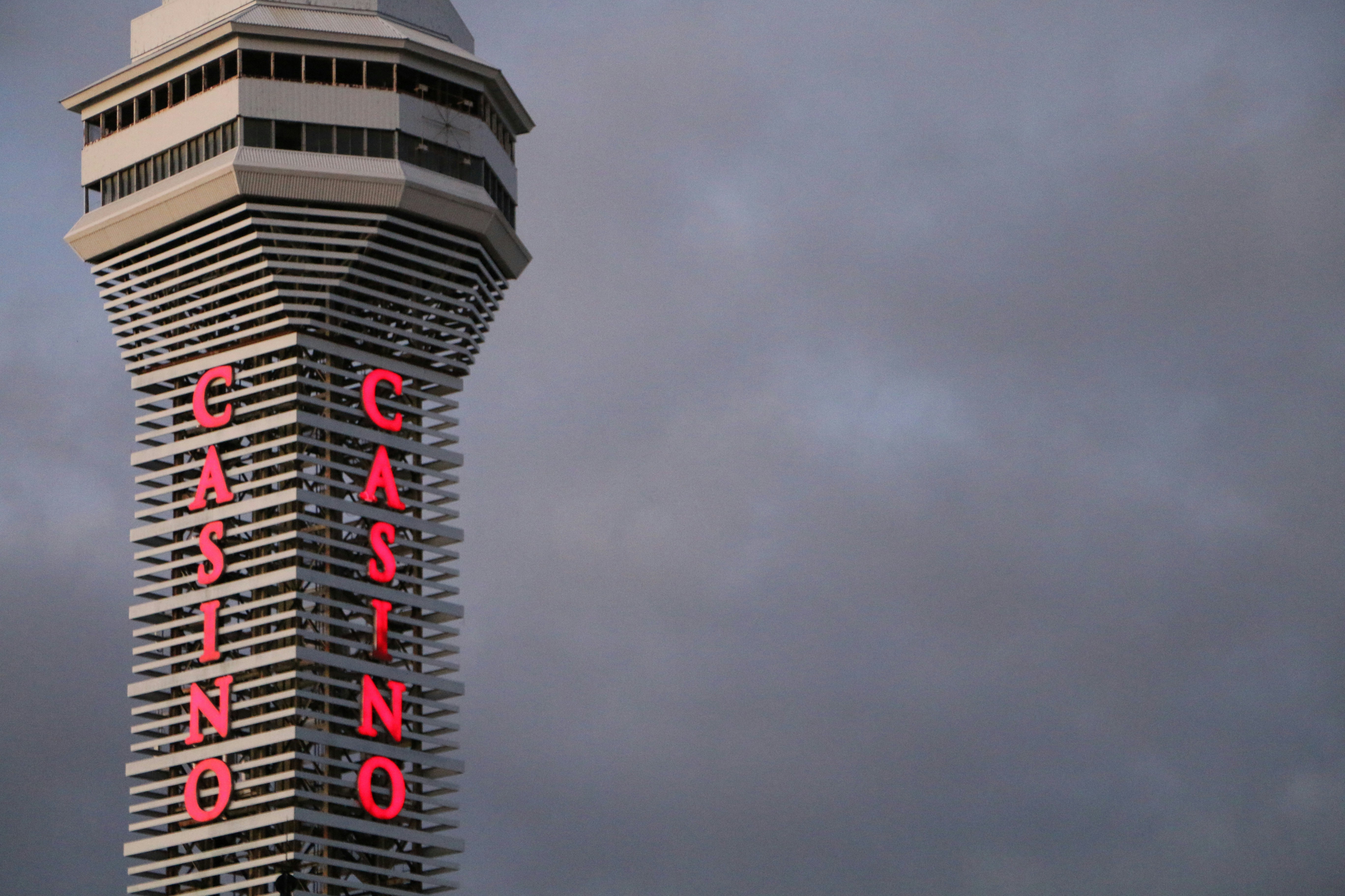 Skyscraper with large red casino sign against cloudy sky