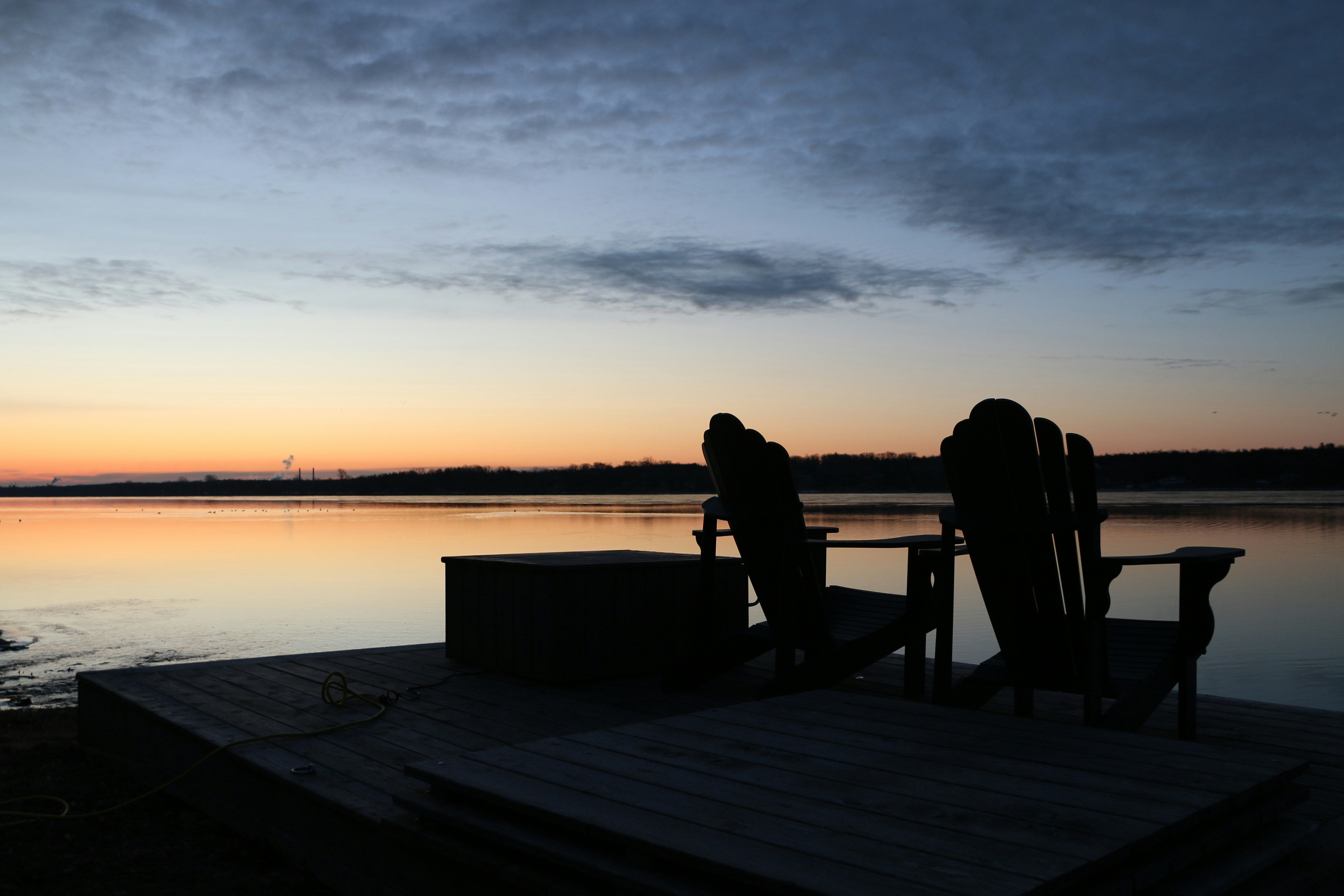 Two chairs on a dock at sunset