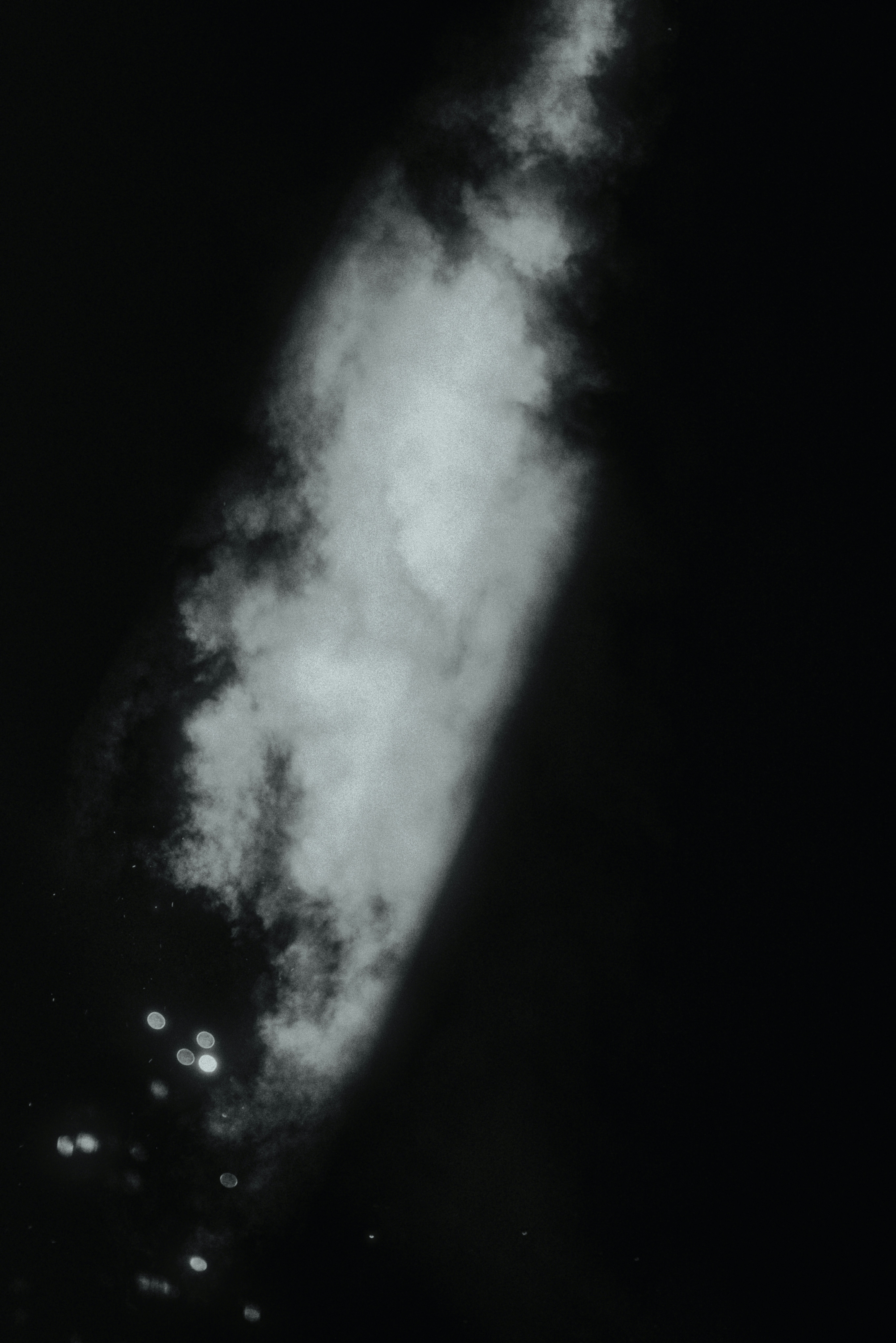 Asap putih dengan latar belakang hitam dengan lampu bokeh.