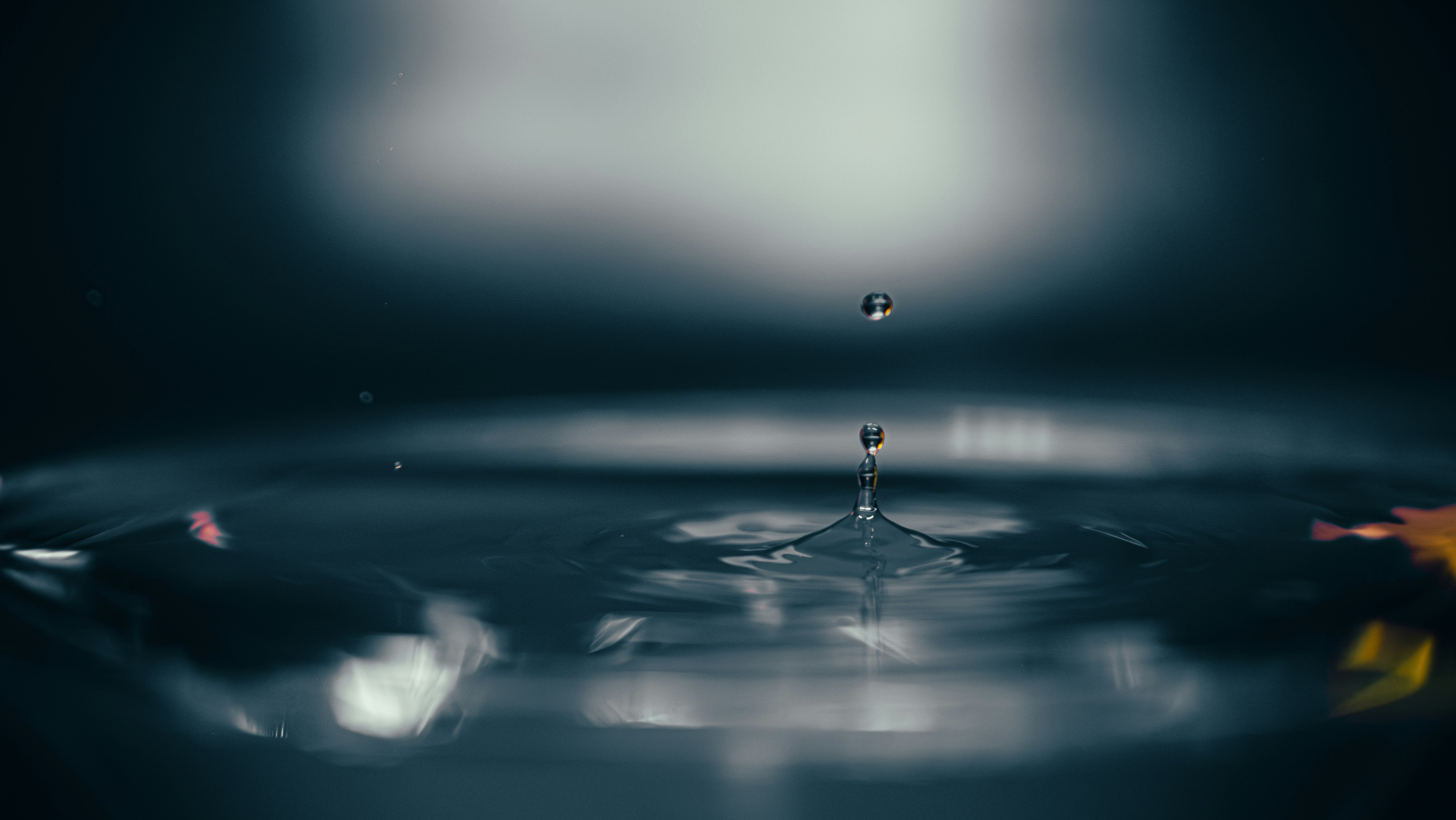 Ein Wassertropfen, der in die kräuselnde Wasseroberfläche fällt.