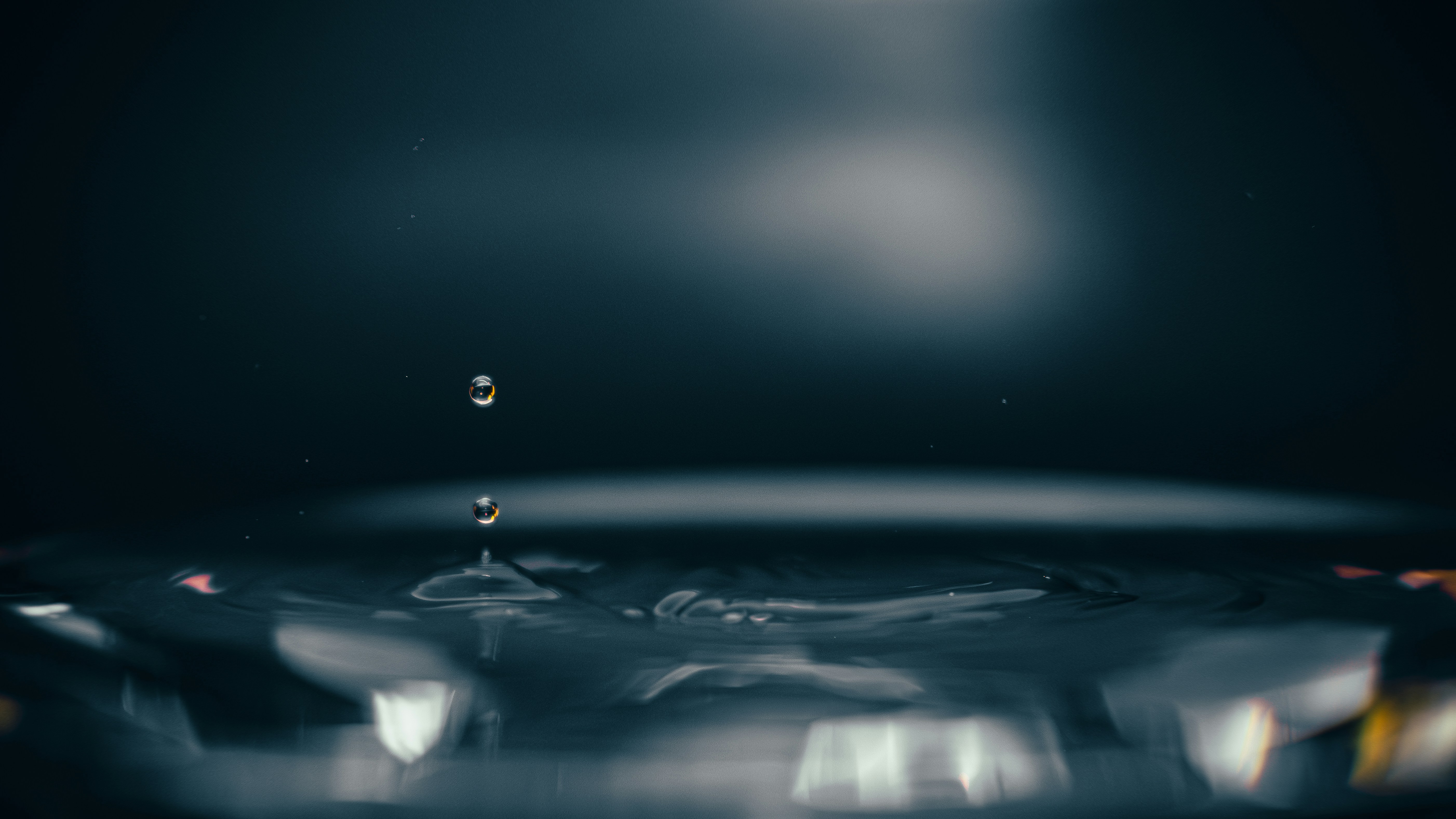 Wassertropfen, der in die dunkle Wasseroberfläche fällt