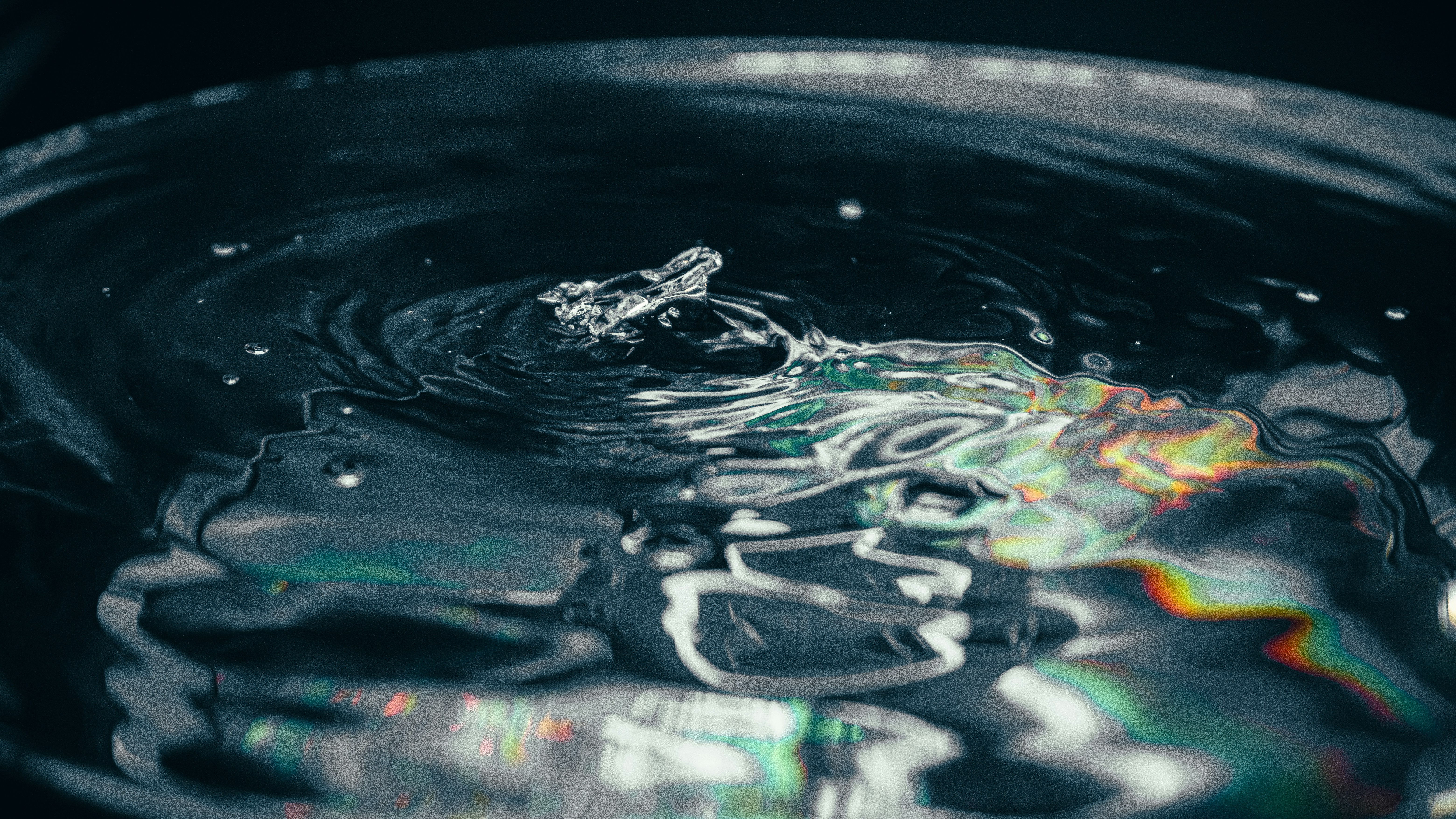 Wassertropfen, der ins klare Wasser spritzt und Wellen erzeugt