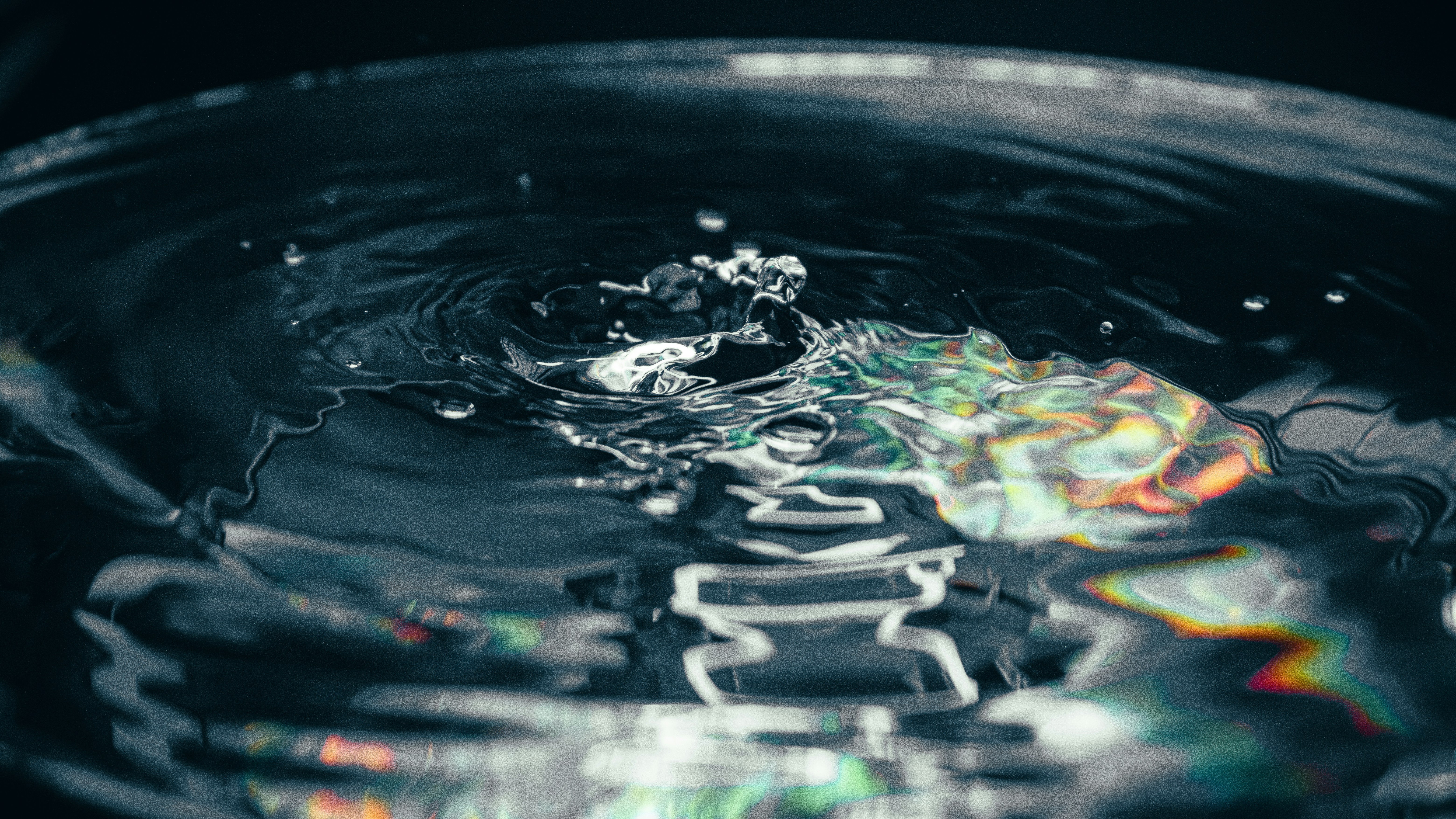 Wasser, das in einer dunklen Schüssel mit Spiegelungen spritzt