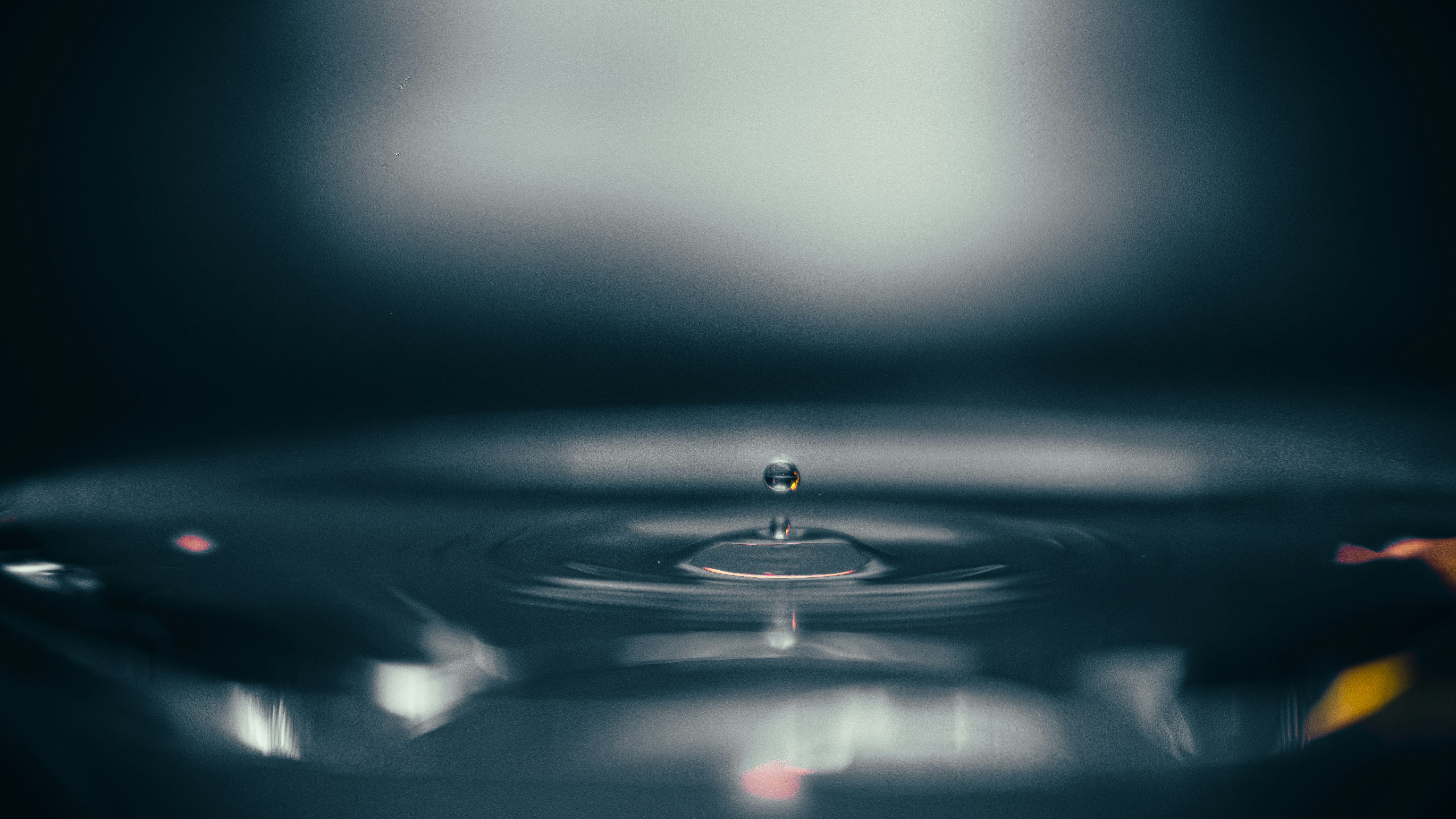 Ein einzelner Wassertropfen, der in ruhiges Wasser fällt