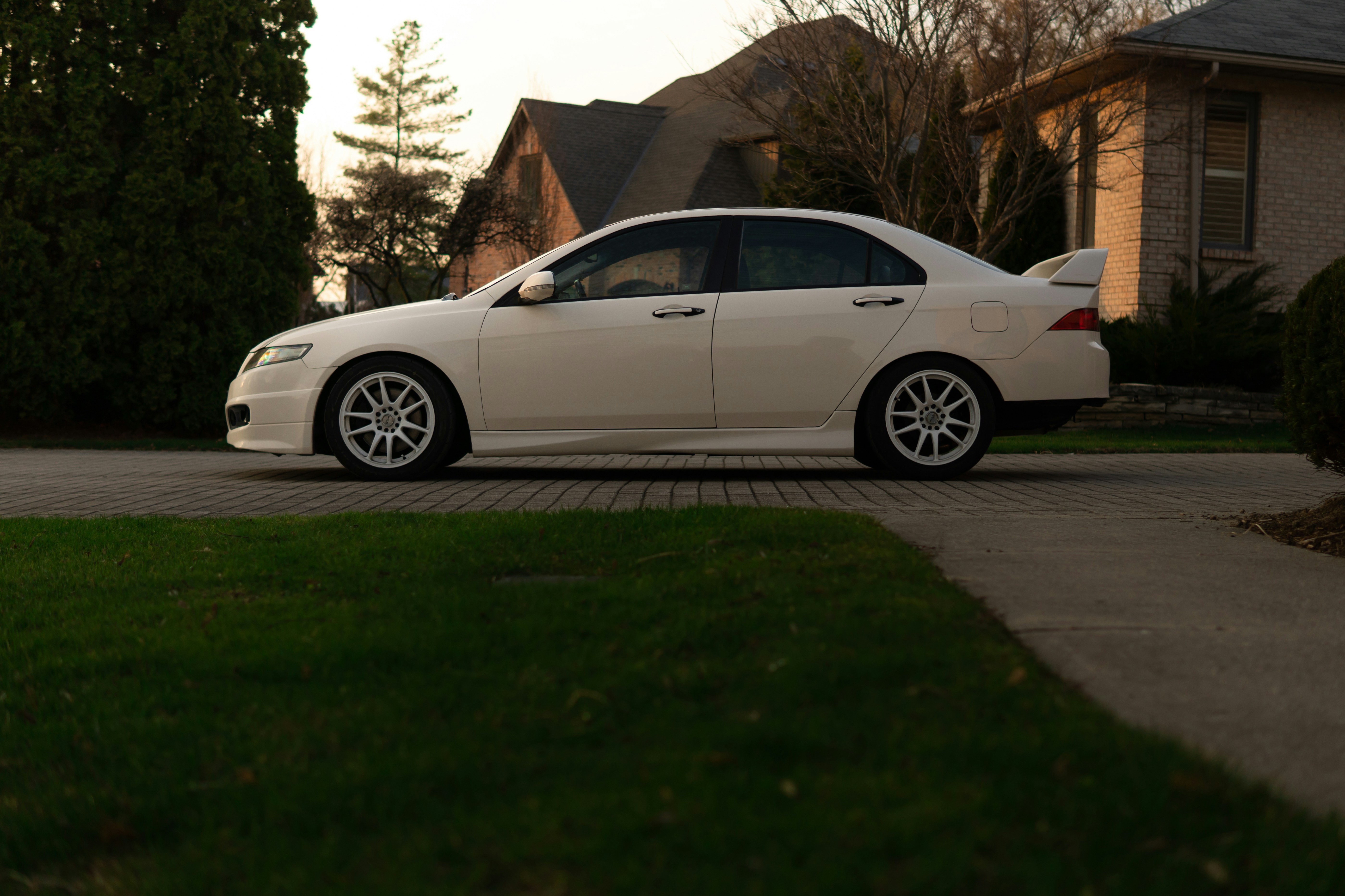 White sedan with white rims parked on street.