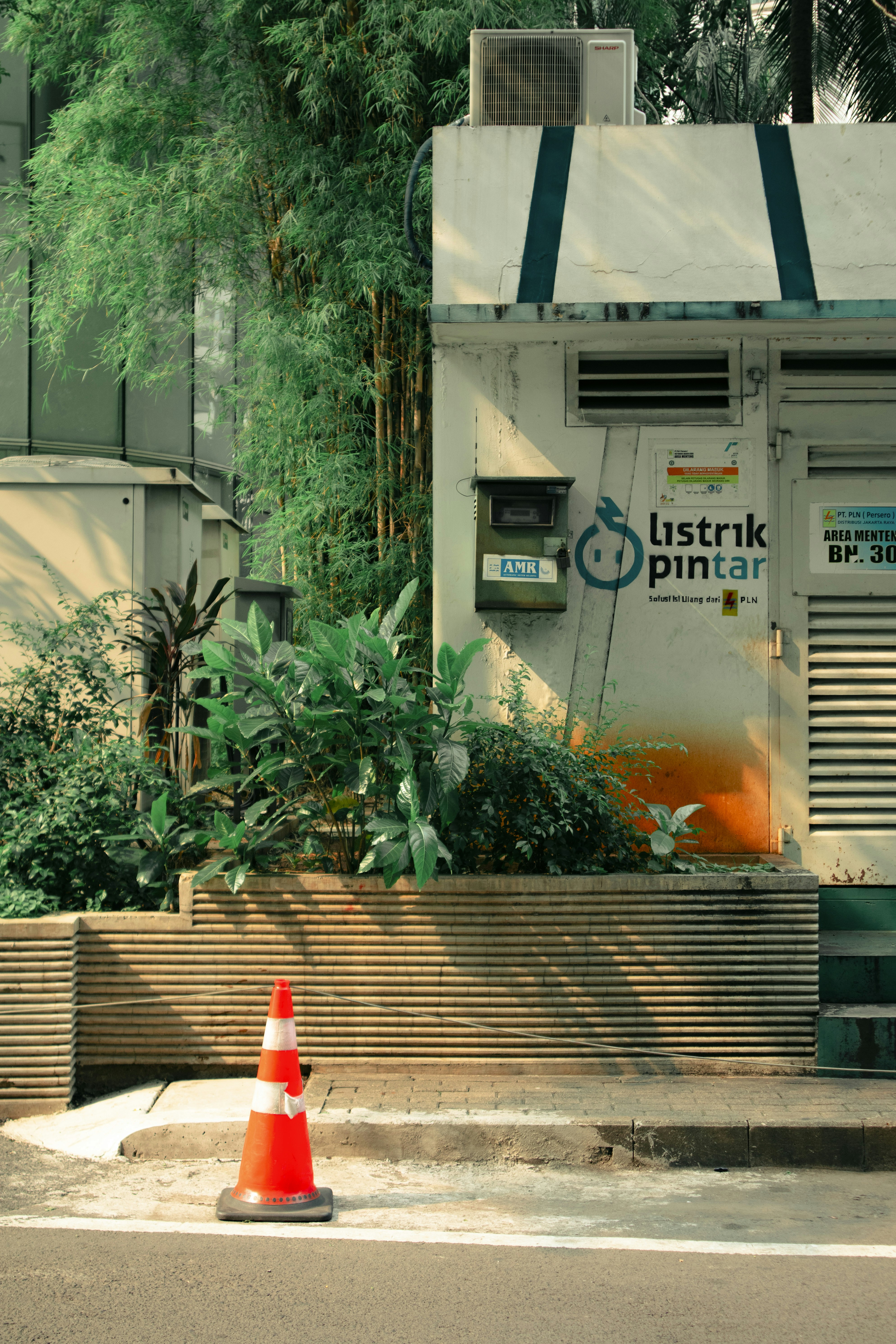 Orange traffic cone stands on a sidewalk near a building.