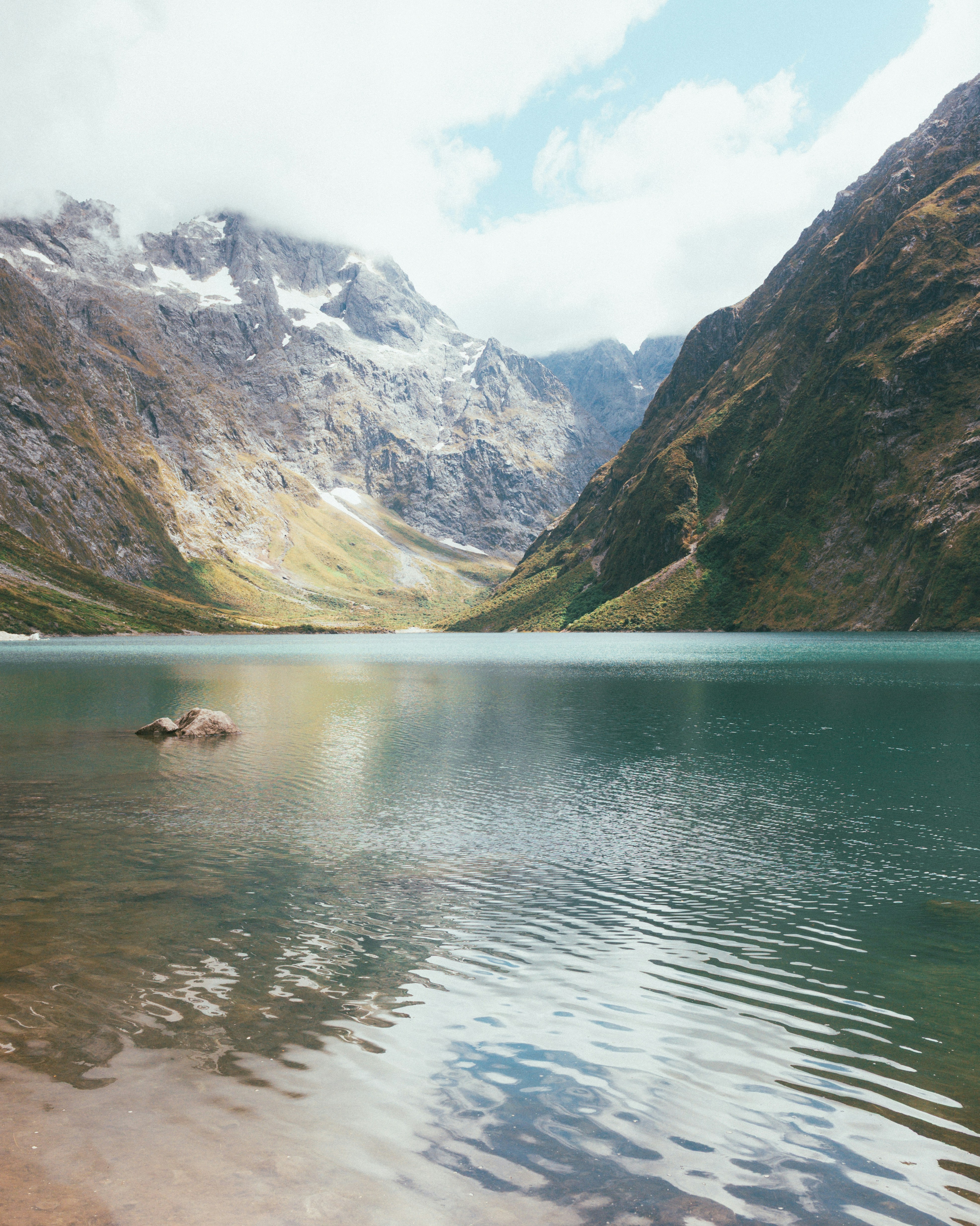 Turquoise lake surrounded by rugged mountains under a cloudy sky